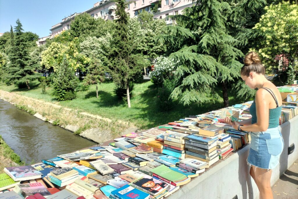 a second hand book market on a bridge over a river in Tirana