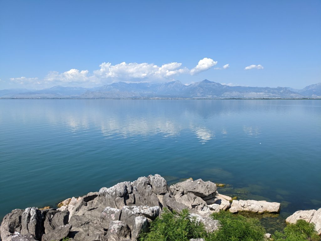 view over the calm water of Lake Shkoder with mountains in the background