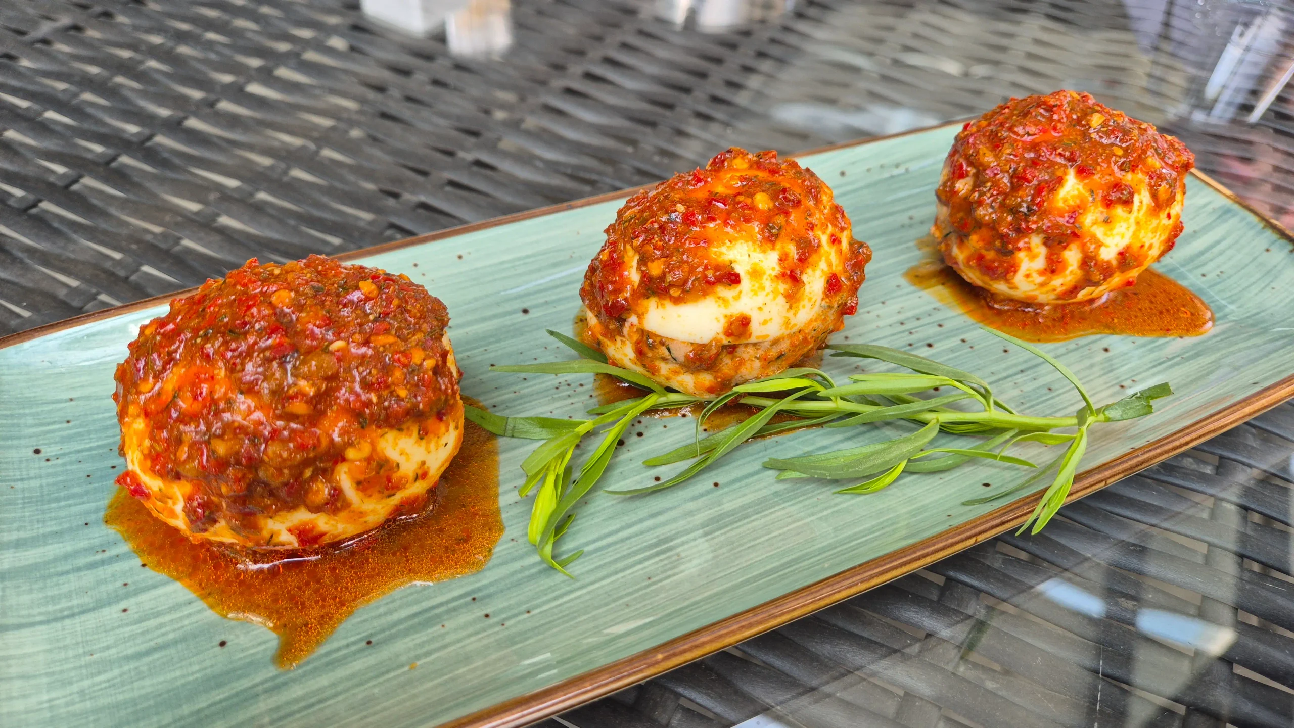 a plate of three boiled eggs stuffed with Georgian walnut paste and topped with adjika chilli sauce -Abkhazian akataghchapa