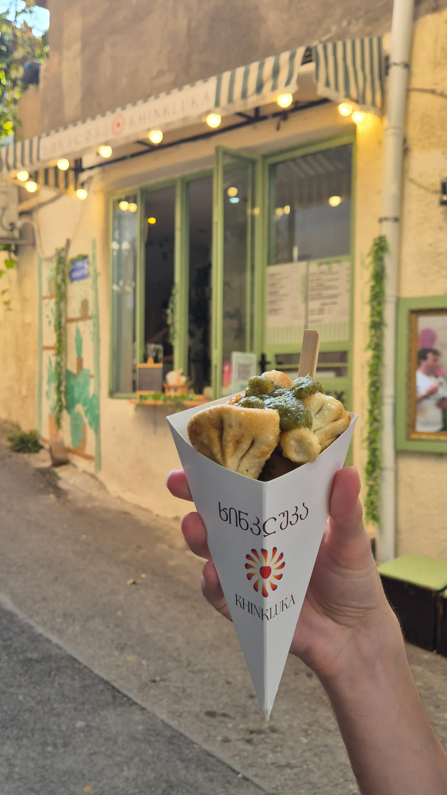 a cone of mini mushroom fried khinkali topped with a green herby tkemail sauce - vegetarian restaurants in Tbilisi