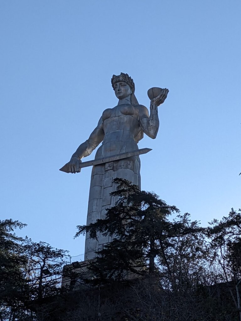 Mother of Georgia statue is tall and metal in a very Soviet style. She holds a sword in one hand and a bowl of wine in the other - Tbilisi