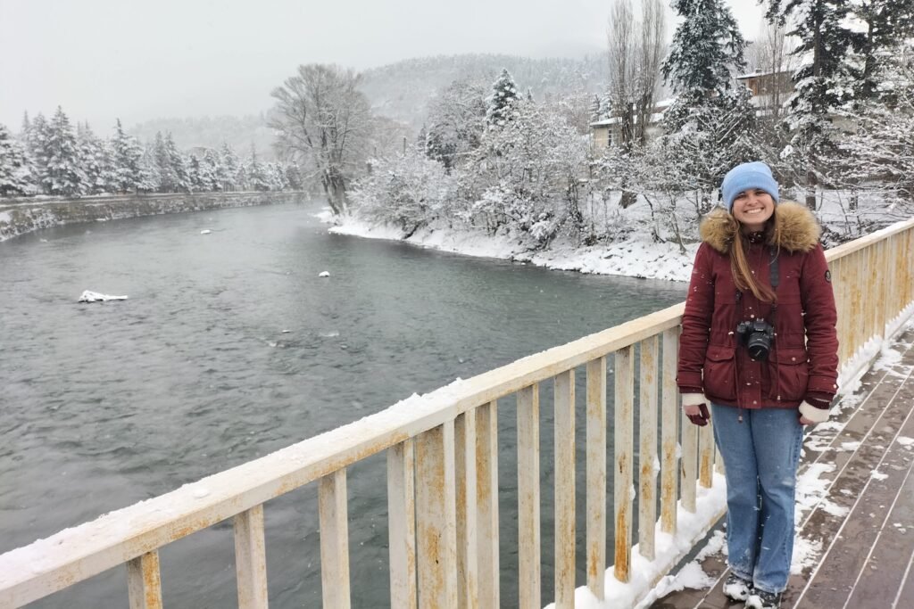 Borjomi in winter a woman stands on a bridge overlooking a river in Borjomi with snow on the banks, spots in Georgia you can reach by train