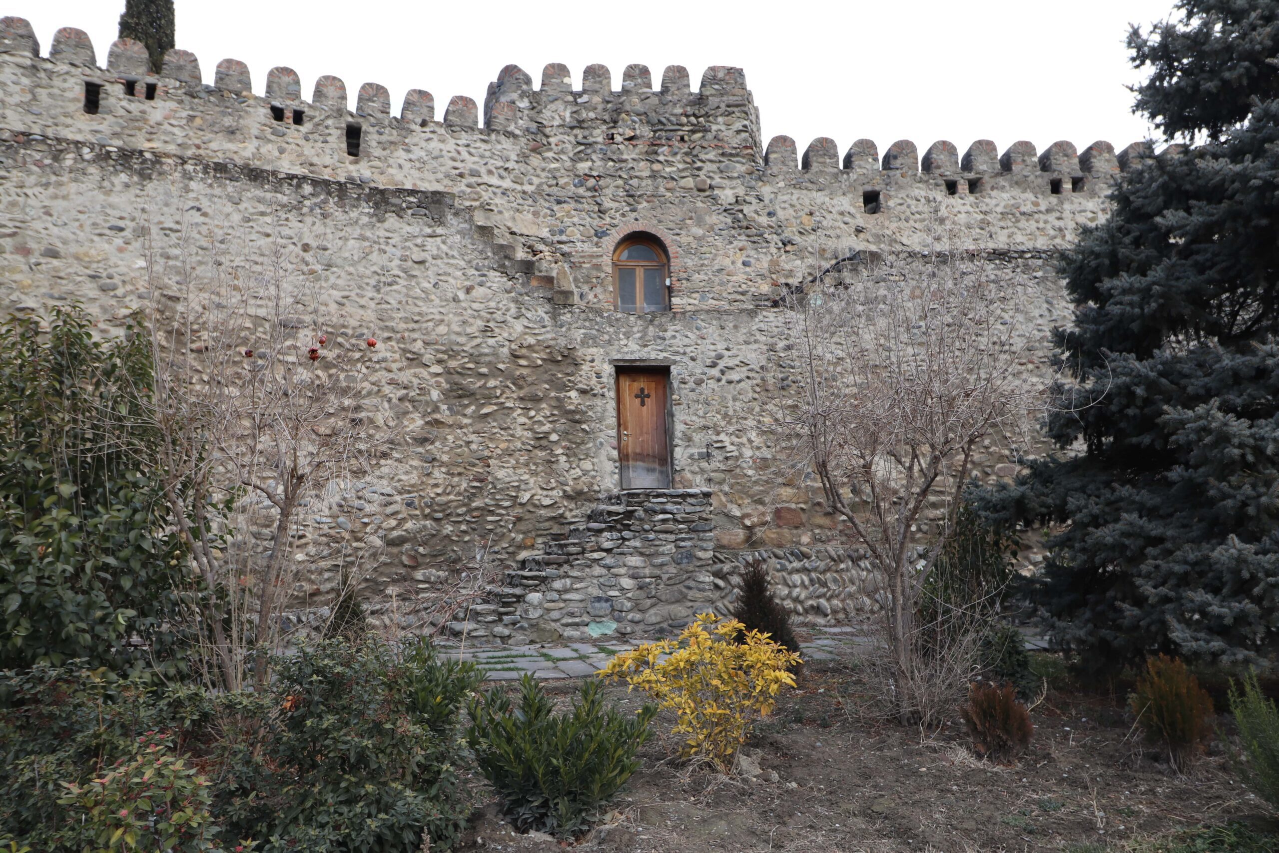 a stone wall with a wooden doorway in Mtskheta, Georgia