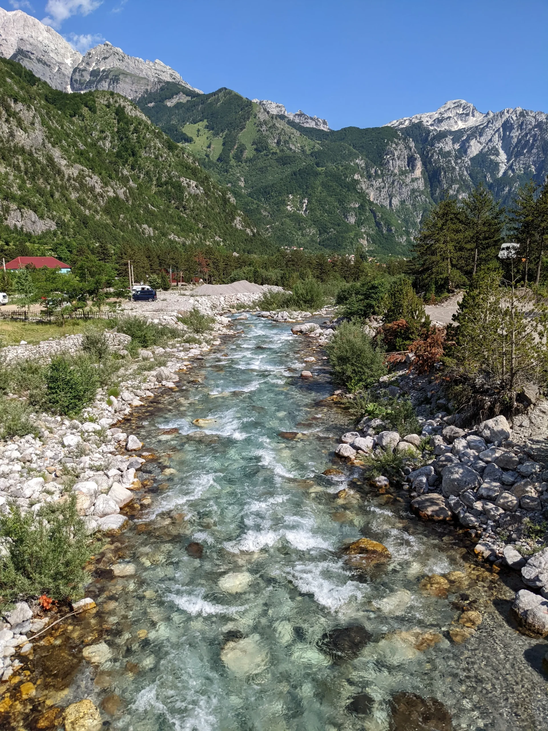 a crystal clear river runs through the snow-capped mountains of the Albanian Alps