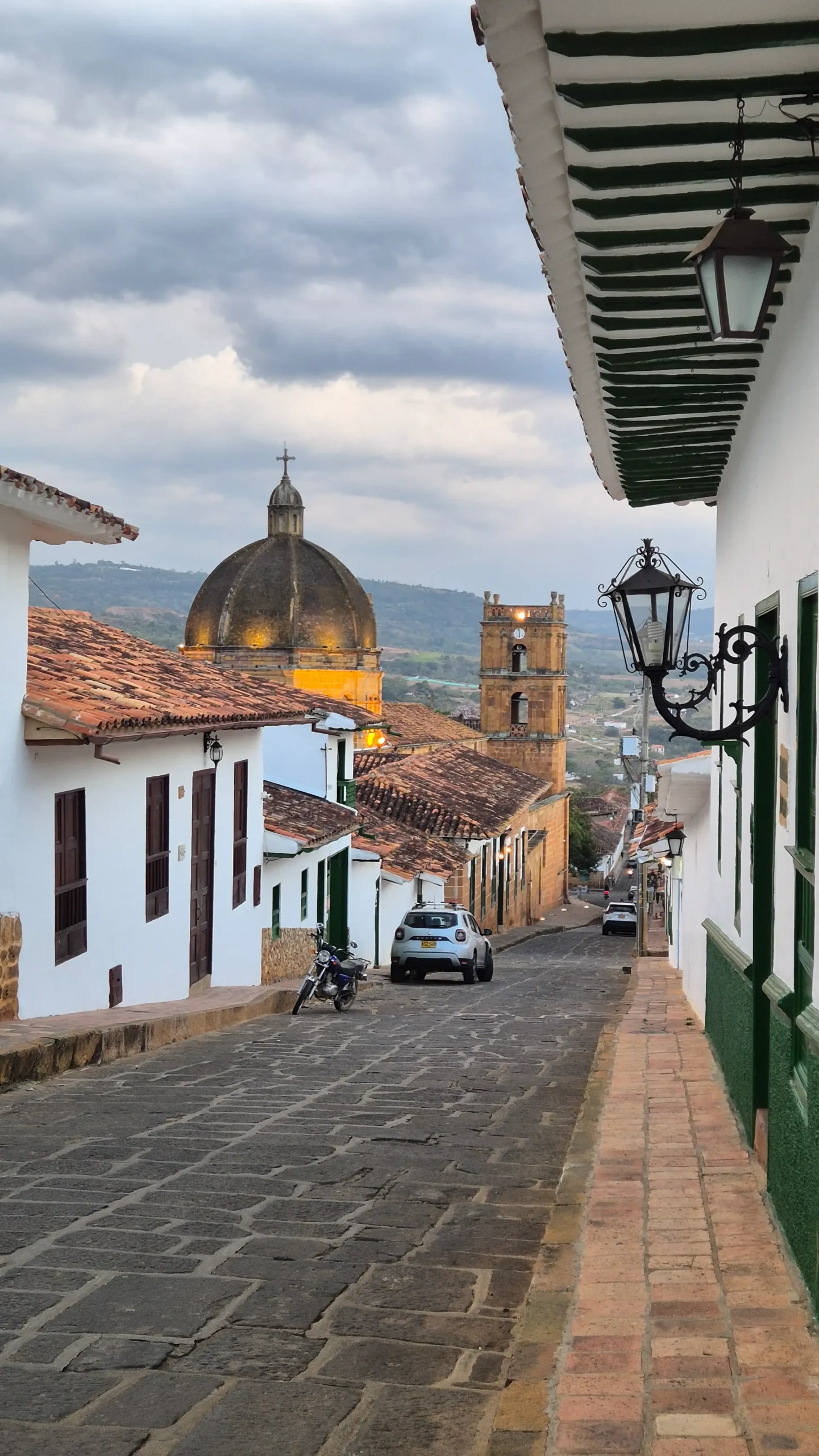 Barichara, Colombia a view down a street in Barichara, Colombia shows cobblestones, a church, orange roof-tiles, and street lamps