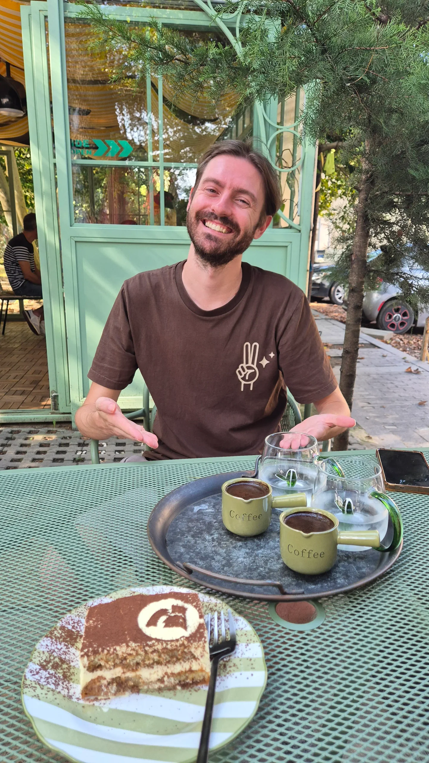 EFEK Tiramisu Kutaisi a man sits at an outside table with a plate of tiramisu and two cups of Turkish coffee - EFEK Tiramisu, Kutaisi