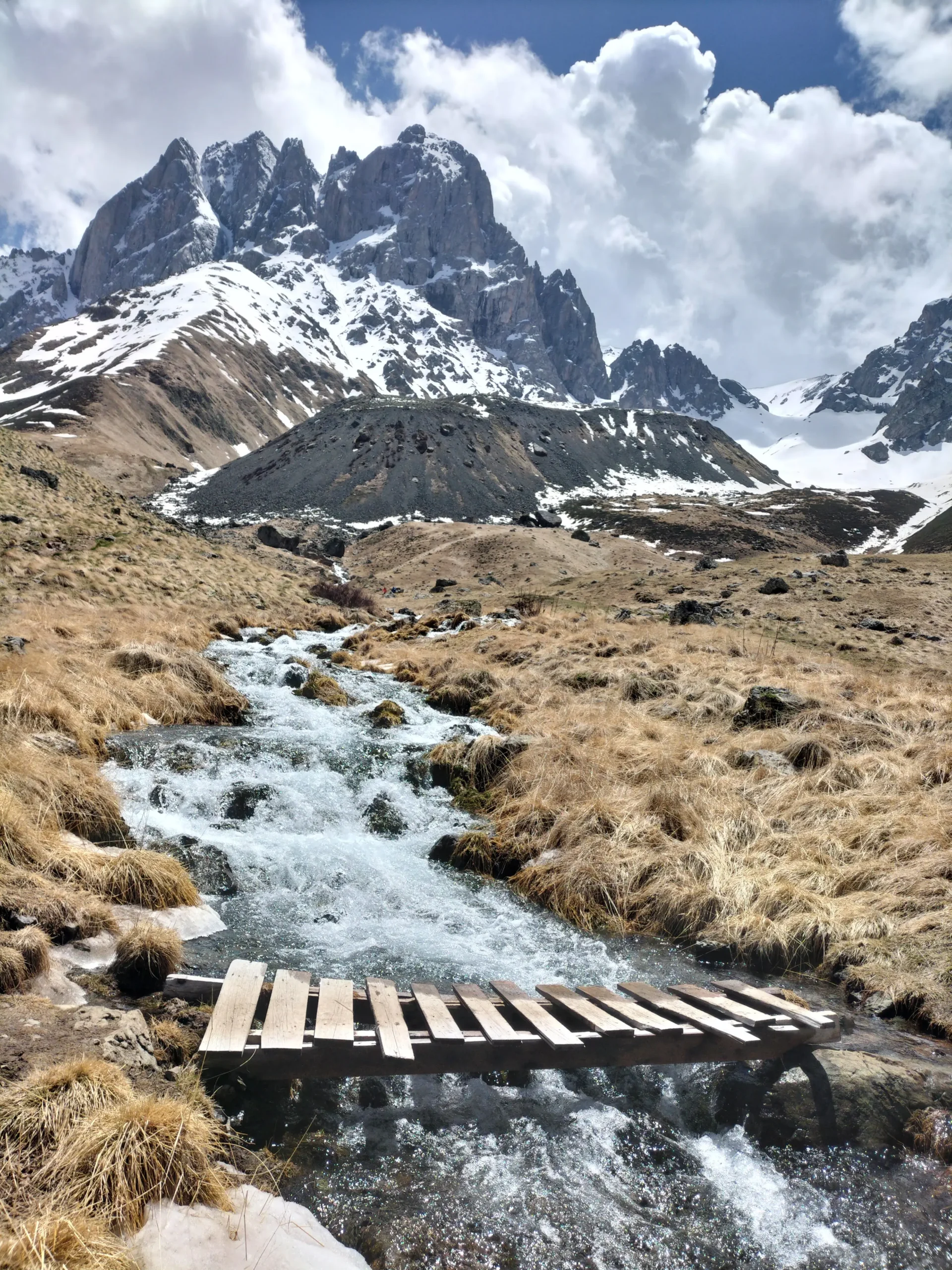 Juta Valley a snow-capped mountain has a river running in front of it and a very hand-made wooden bridge to cross the river in Juta Valley. Unique things to do in Georgia