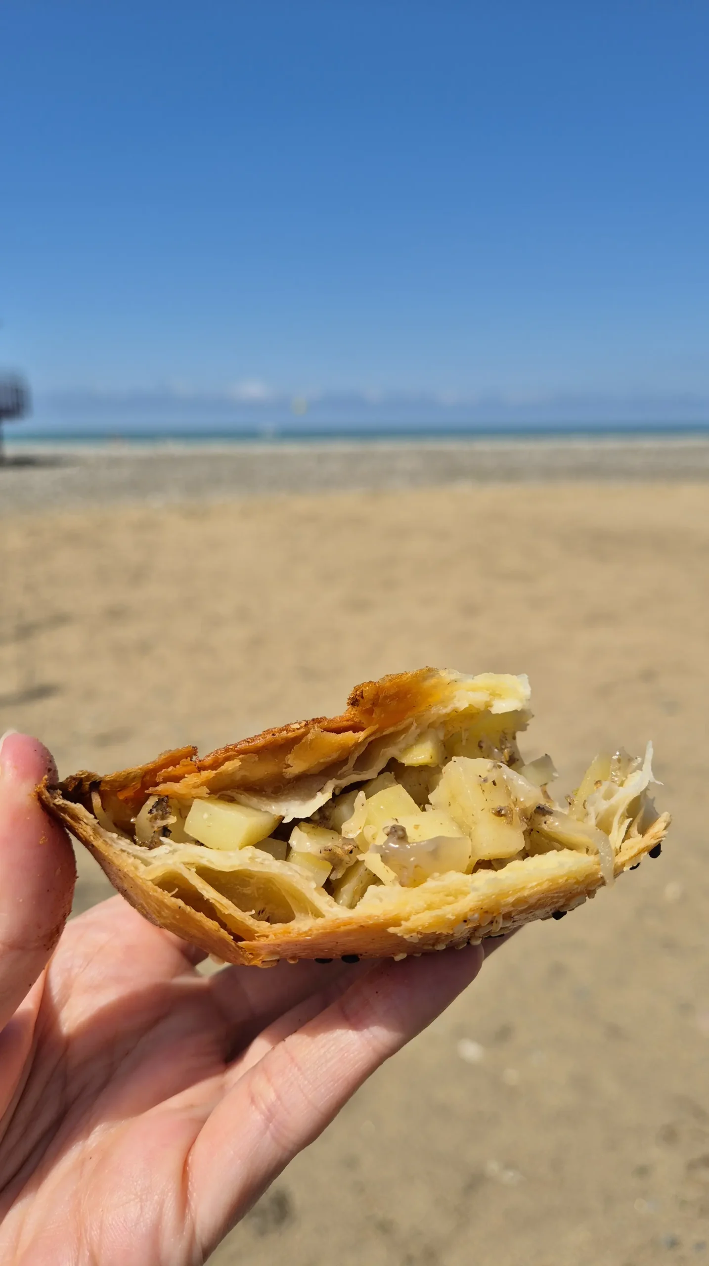 Uzbek samsa a cross section of a potato samsa from Uzbek Tandoor in Batumi is held up with a beach background and blue skies