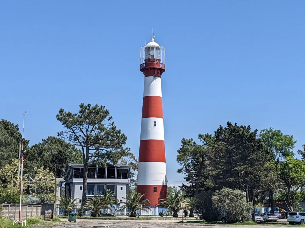 Don't Fancy a Marshrutka? Here are 8 Spots in Georgia You Can Reach by Train 2 a red and white striped lighthouse stands amongst green trees and a blue sky in Poti, Georgia