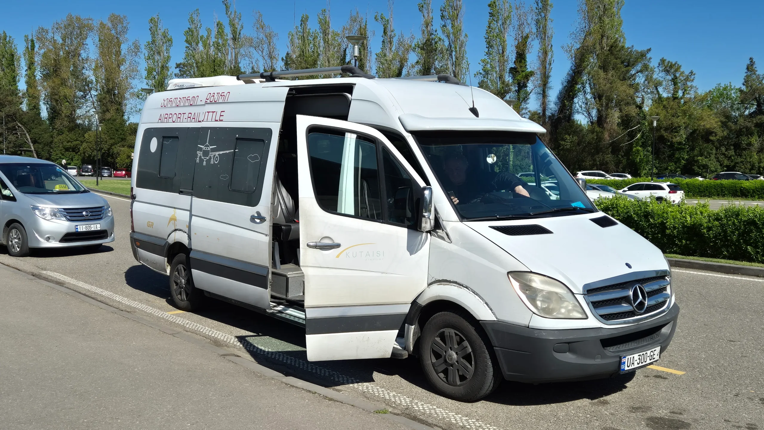 Kutaisi airport shuttle a white marshrutka (minivan) is parked at the side of the road