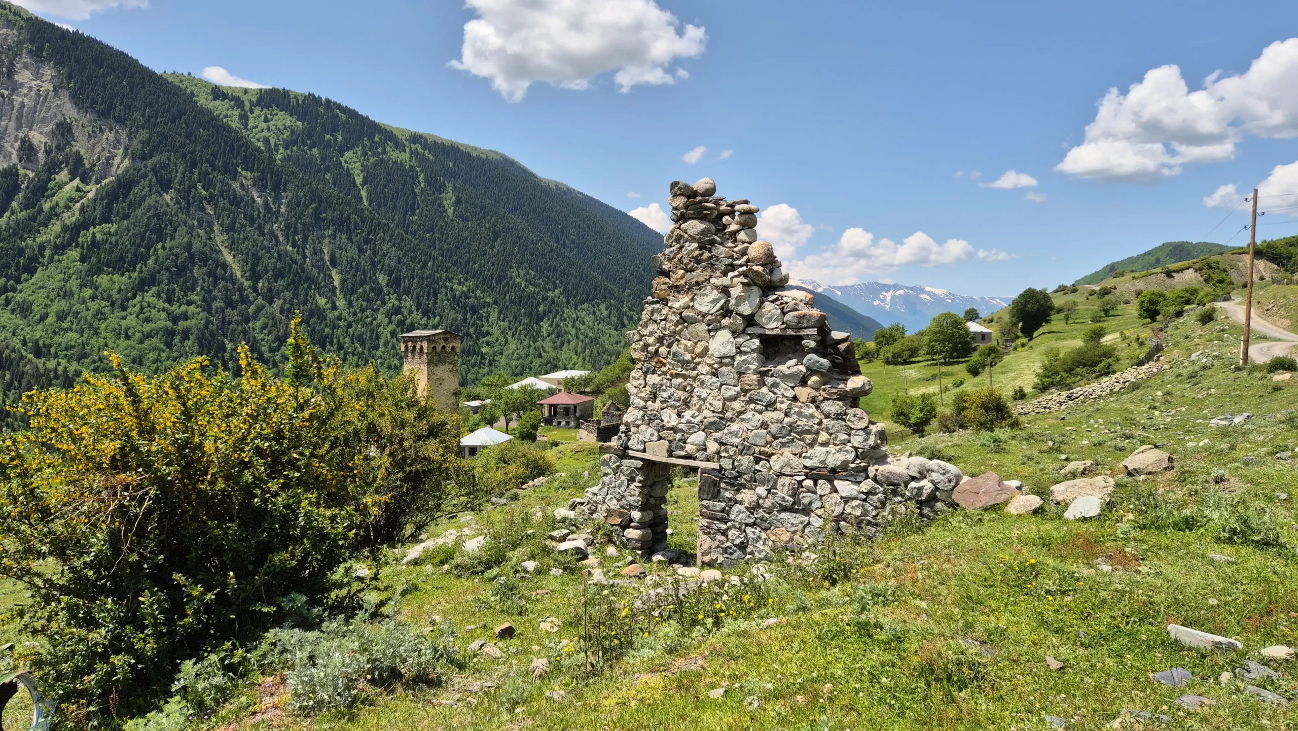 Ruins of a building ruins of a building with a doorway remaining, Svan watchtower in the background on the hike from Mestia to Zhabeshi, Georgia