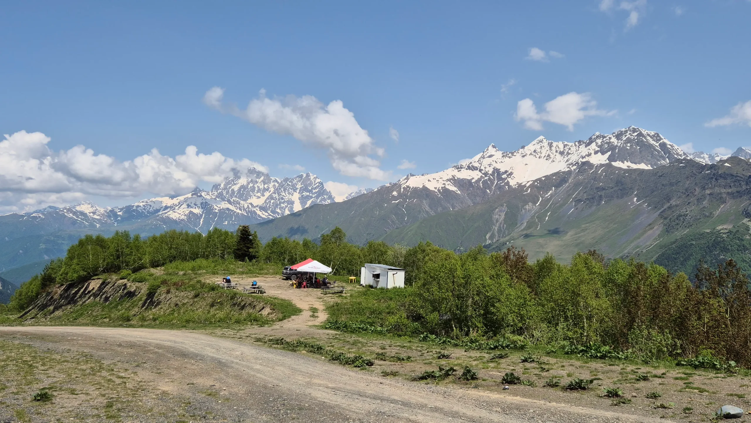 Midway Cafe Zhabeshi to Adishi a cafe at the midway point on the hike from Zhabeshi to Adishi in Georgia is surrounded by trees and two snow-capped mountains