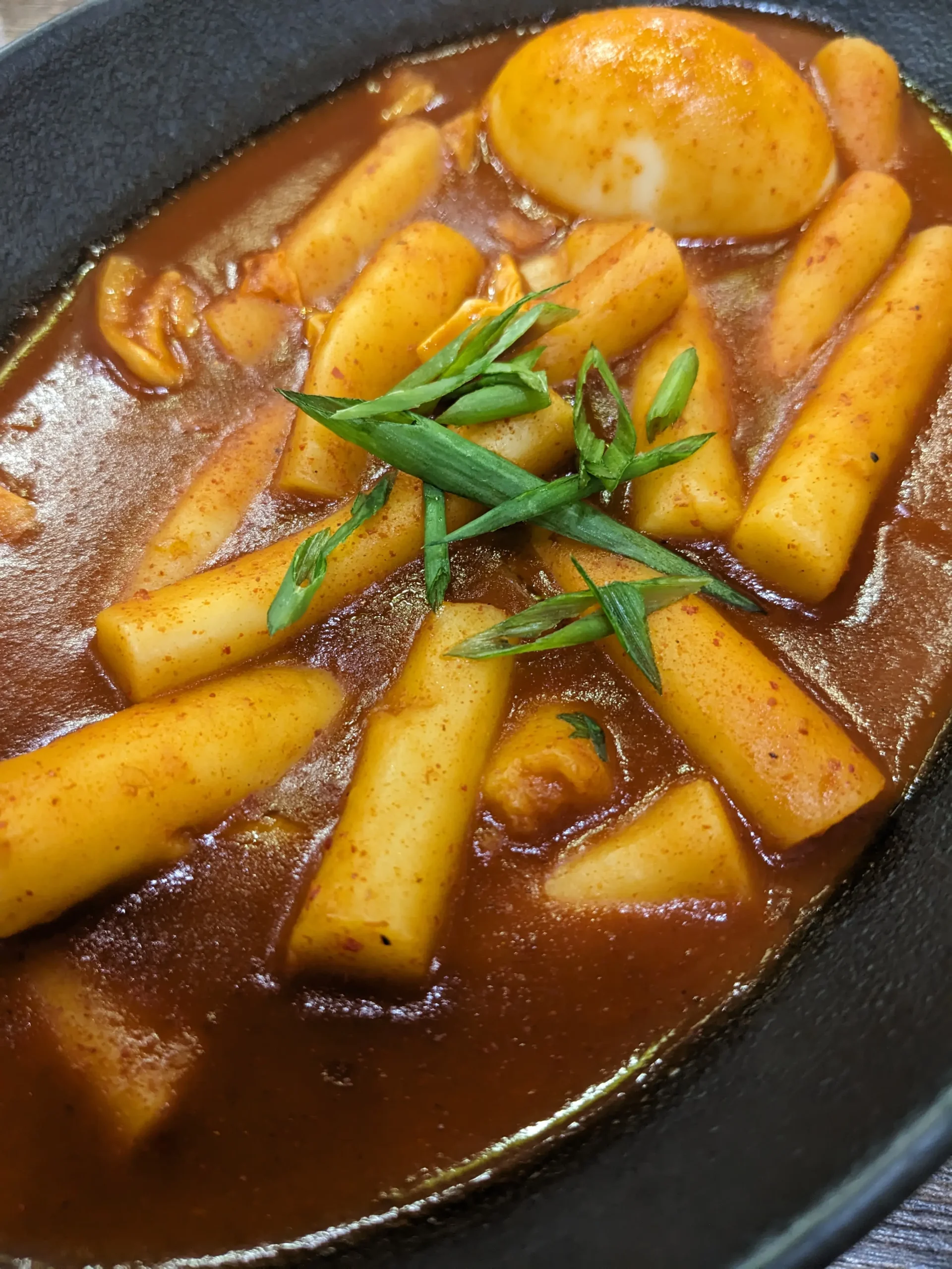 Tteokbokki a bowl of tteokbooki - Korean rice cakes in a gochujang sauce and topped with spring onions at Cooksoo. restaurants in Bishkek for vegetarians, Kyrgyzstan