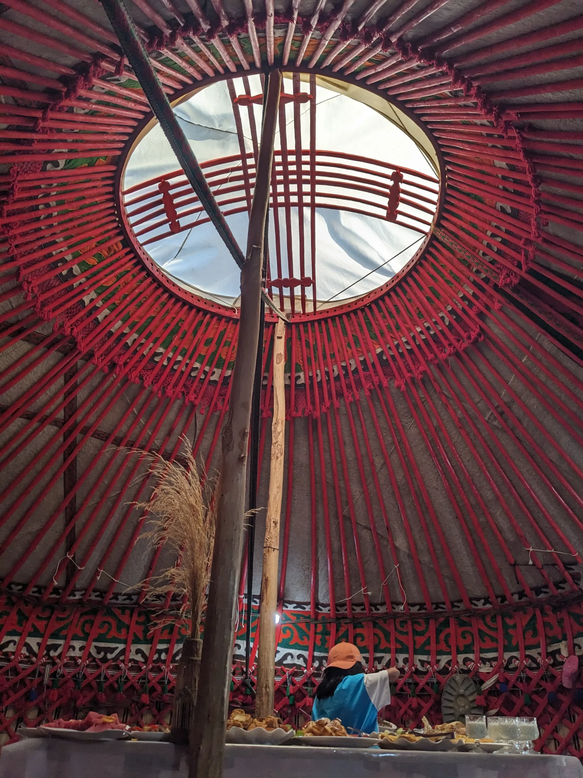 the inside of a traditional Kyrgyz yurt has red wooden poles and patterned material