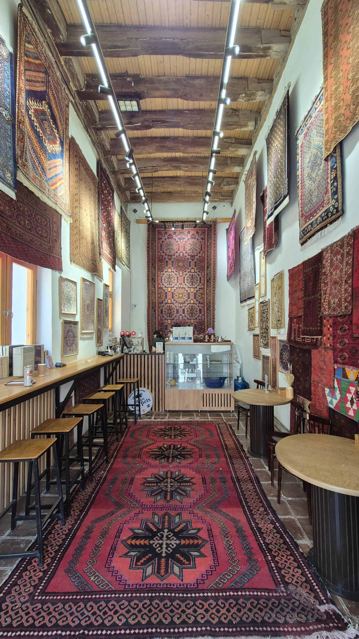 Magic House cafe a narrow cafe has beautiful red carpets with different designs on the floor, and all of the walls in Bukhara, Uzbekistan - Magic House
