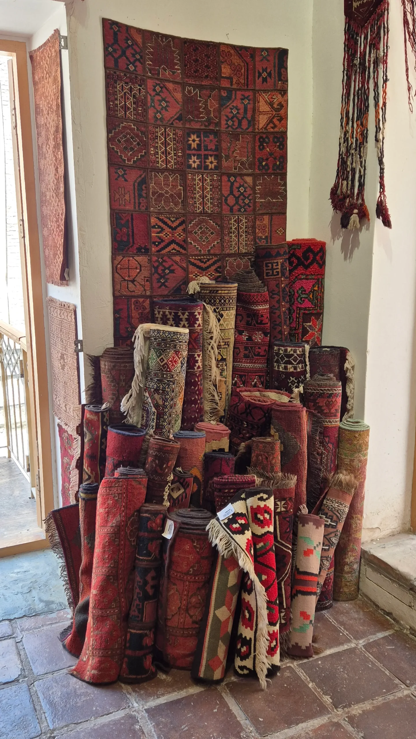 Magic House carpets at least twenty rolls of different sized carpets are all rolled and stacked against a wall lengthways in Bukhara, Uzbekistan