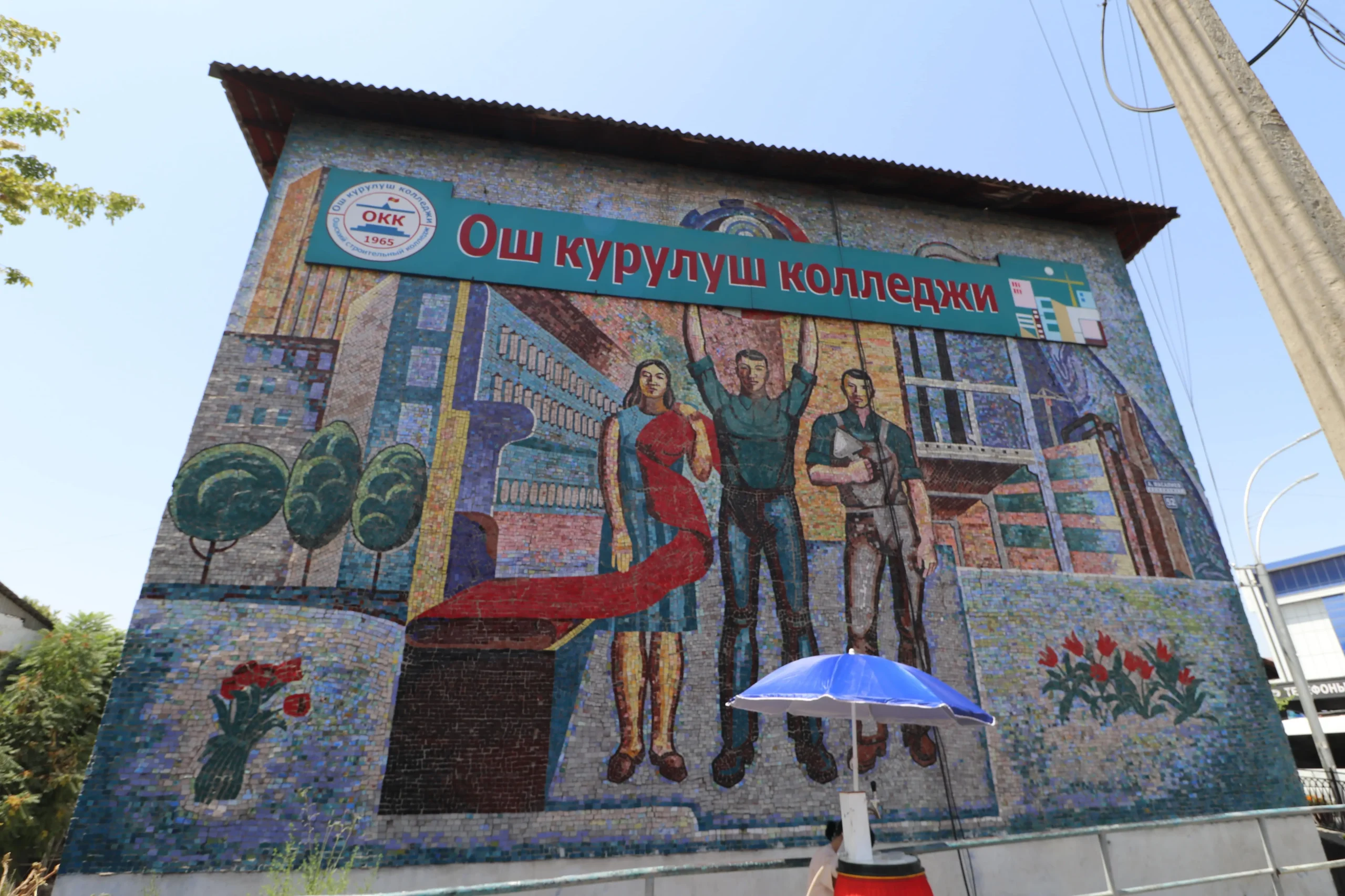 a Soviet mosaic mural in Osh, Kyrgyzstan shows three people and an office 
