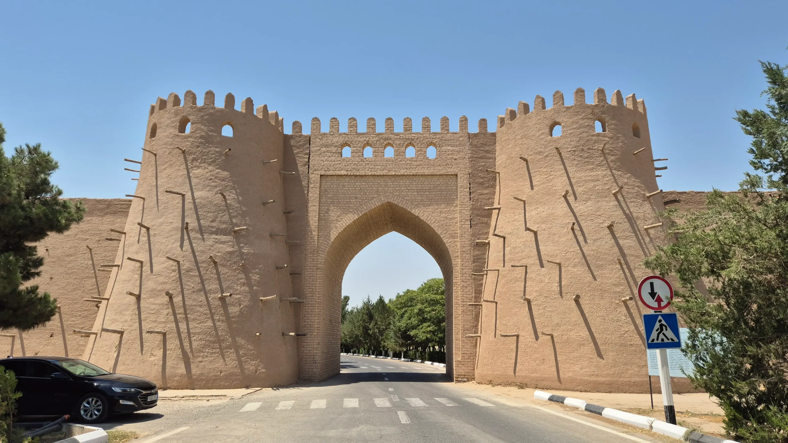 Al Hakim At-Termizi walls brick walls of Al Hakim At-Termizi have two large rounded towers studded with wooden sticks and an archway in between