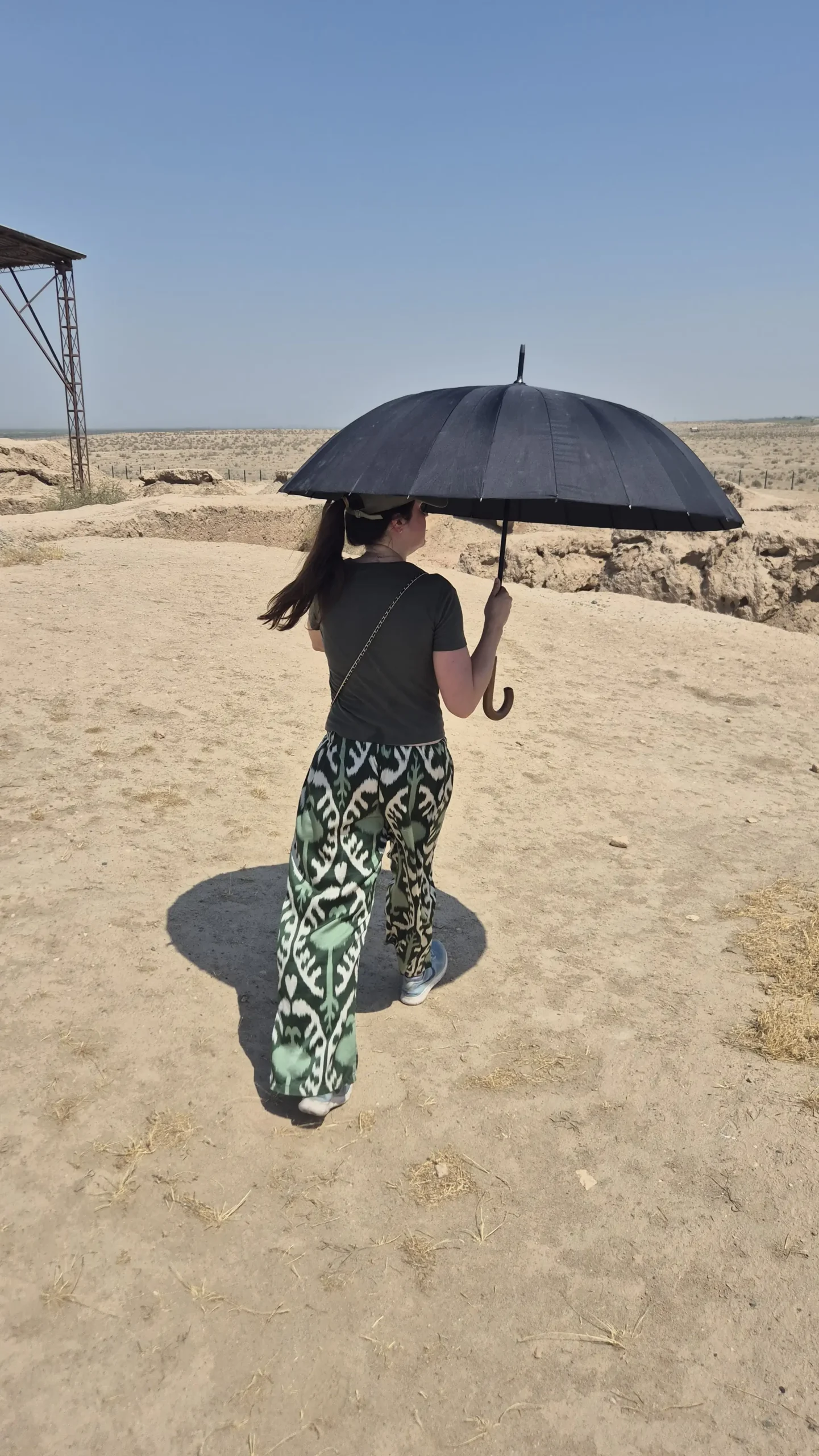 Sam with a black out umbrella a woman is exploring historical sites of Termez while using a black out umbrella to shield from the Uzbek summer heat