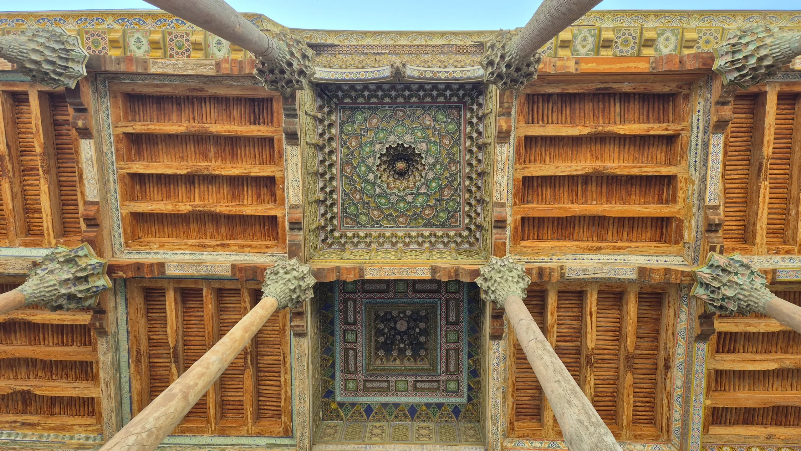 Bolo Hauz ceiling a close up of the ceiling of the facade of Bolo Hauz Mosque in Bukhara, Uzbekistan shows wooden slats, and intricate colourful painting