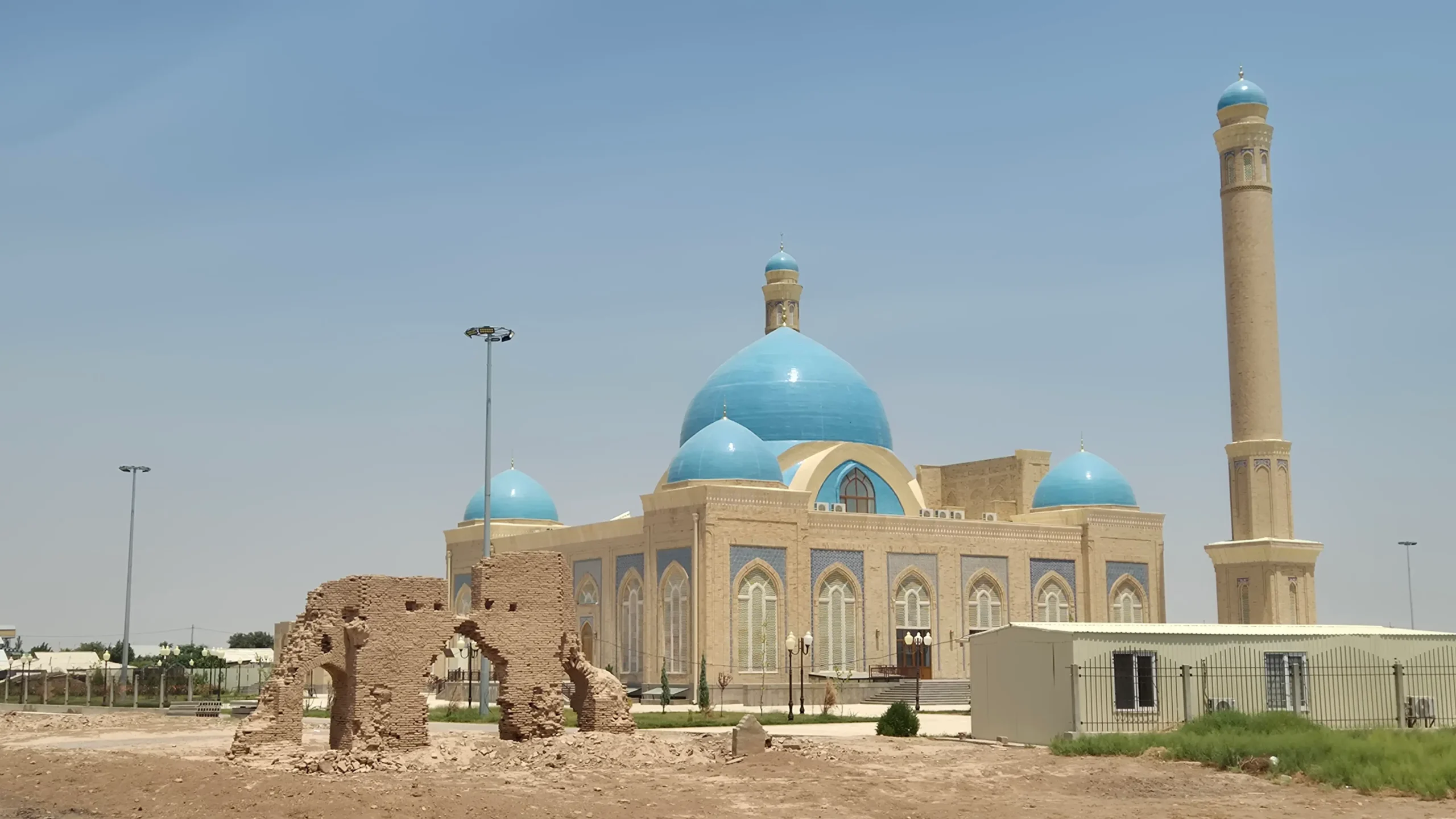 Sultan Saadat Mosque a brick mosque has five domes decorated in pale blue tiles and two minarets. There are ruins of ancient Termez in the foreground.
