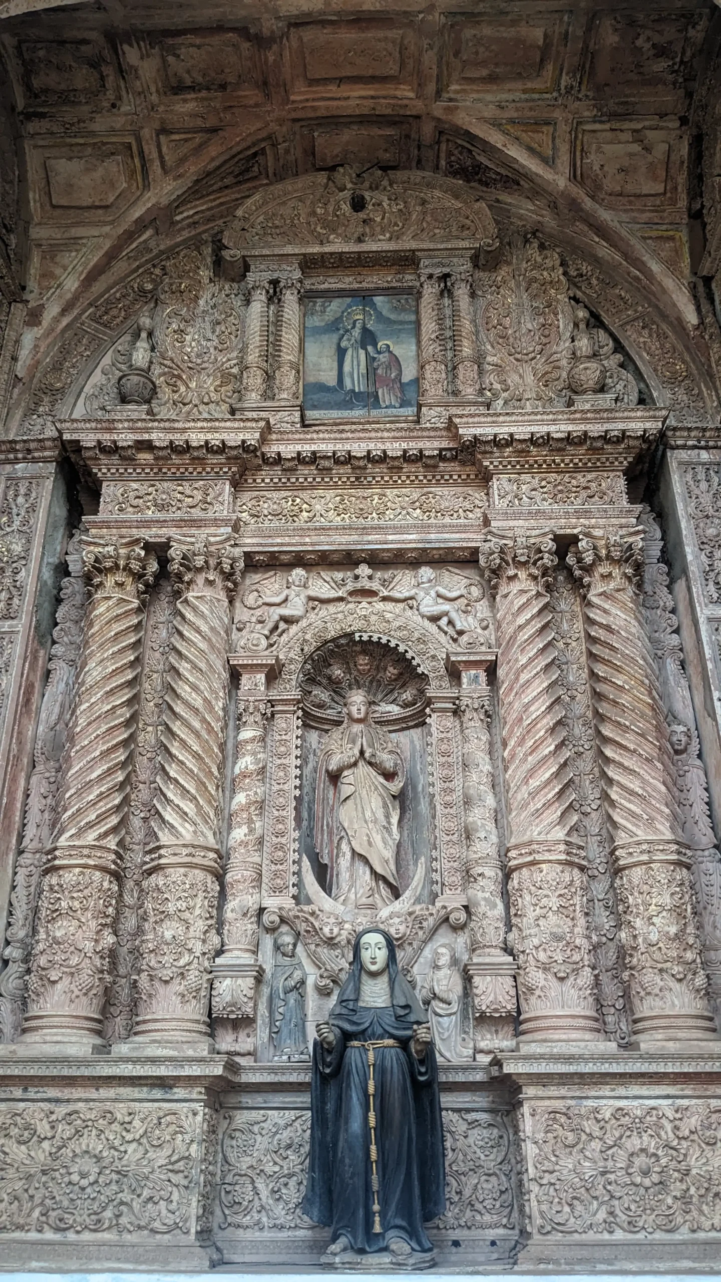 carved altar with pillars. flowers, and people in the church of St Francis of Assisi in Old Goa