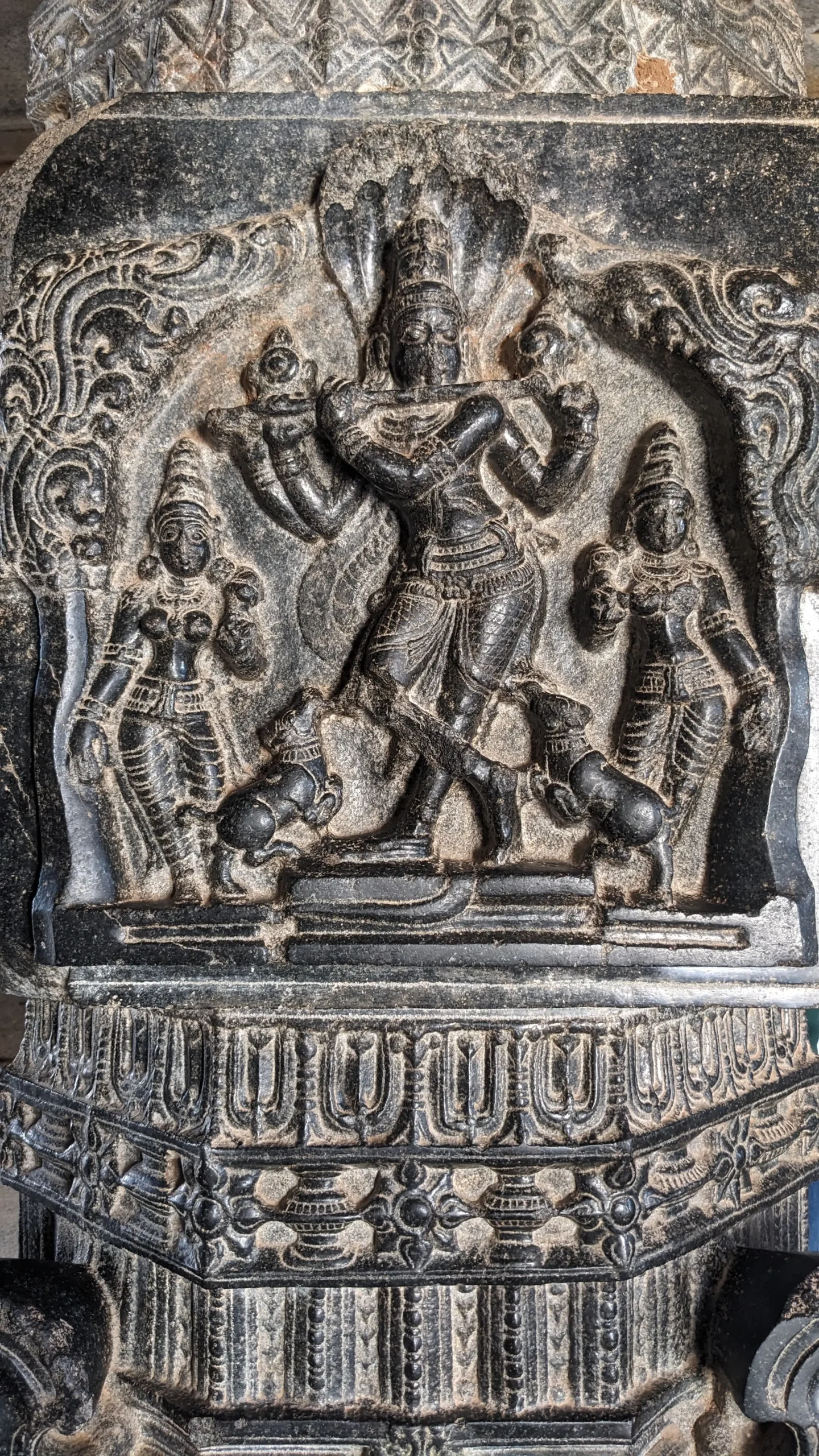 a decorative wall sculpture of three people and two dogs in Hampi, Karnataka, South India