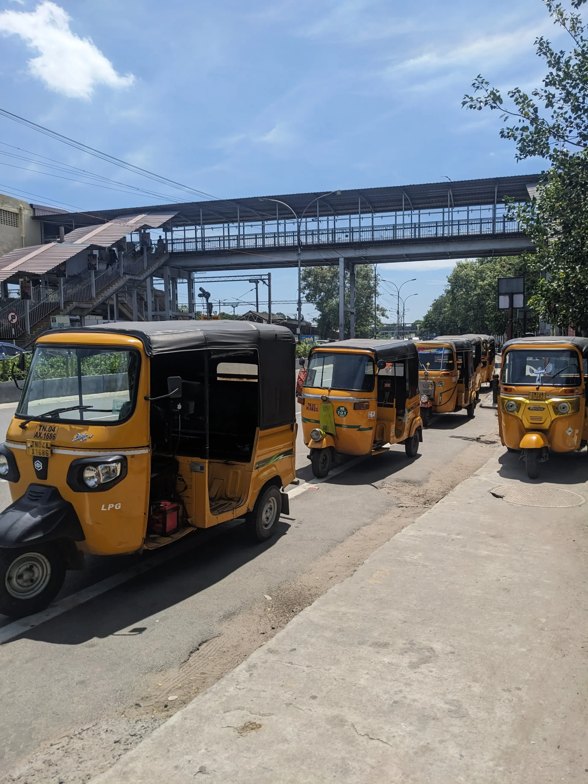 a row of bright yellow tuktuks parked up at the side of the road in Trivandrum, India