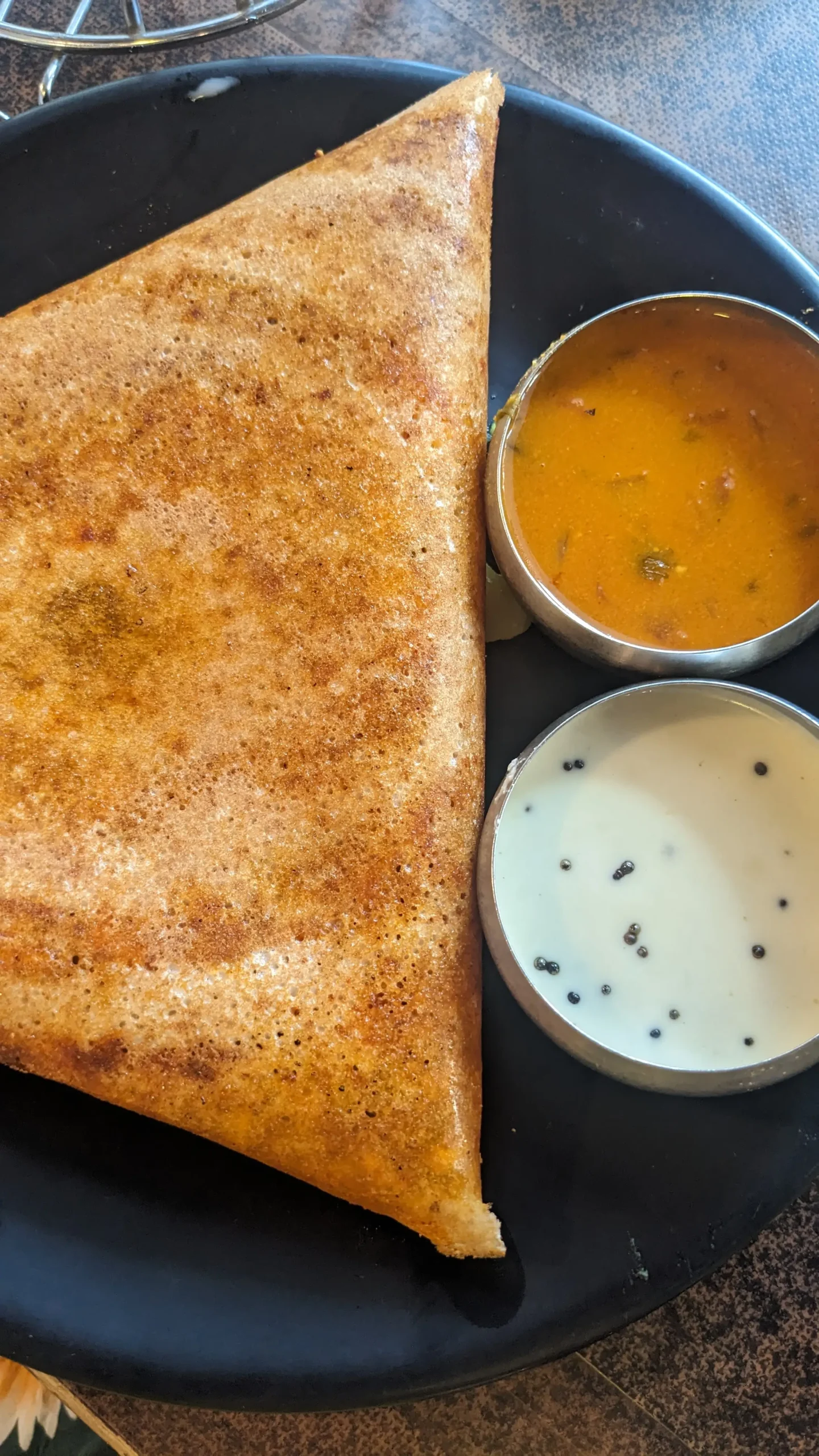 a crisp, folded dosa with two small metal bowls of sambar (watery veg curry) and coconut chutney