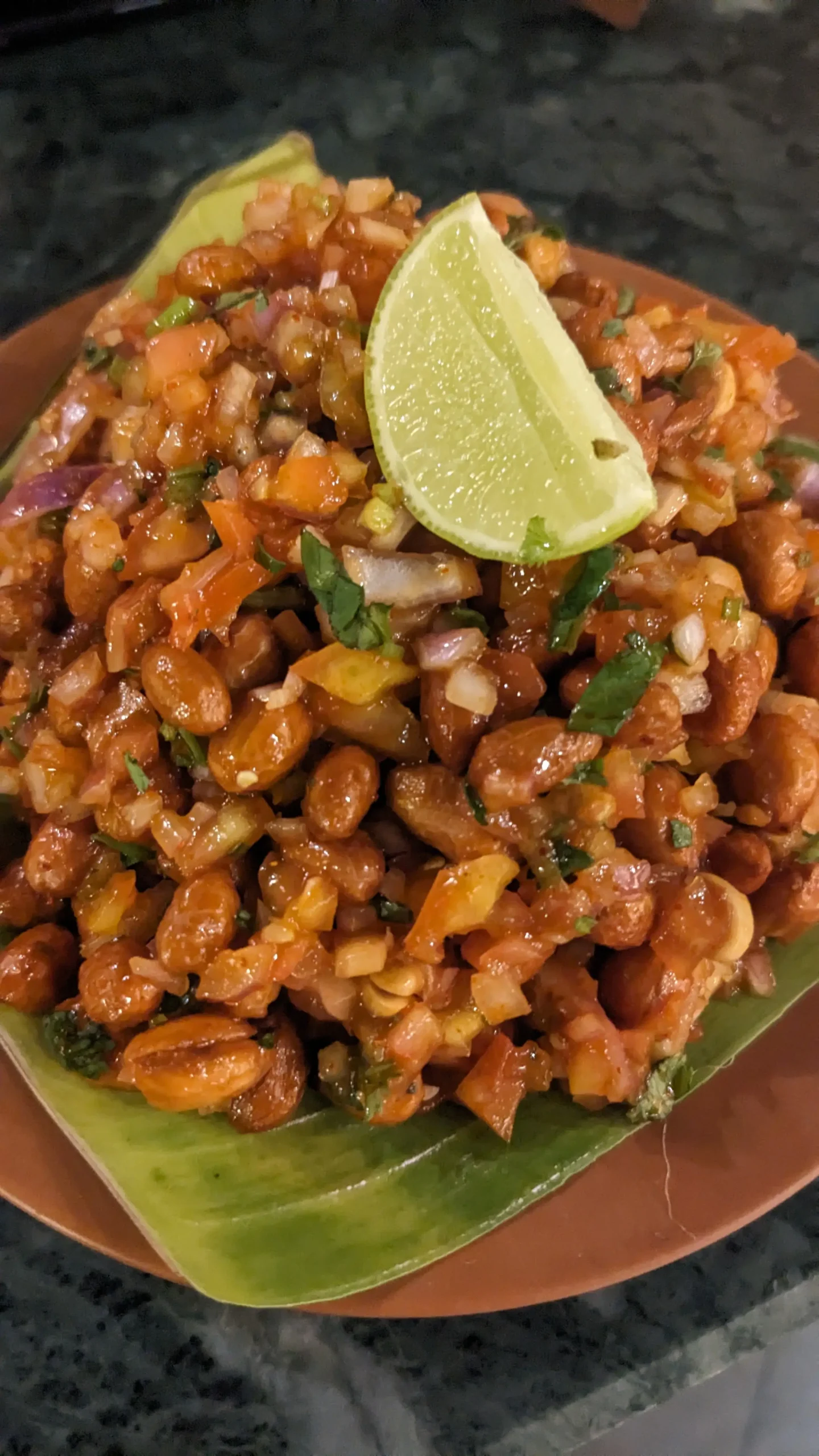 Masala peanuts a bowl of masala peanuts has peanuts, in a sticky sauce with fresh red onion, tomatoes and herbs, with a wedge of lime on top in Goa, India