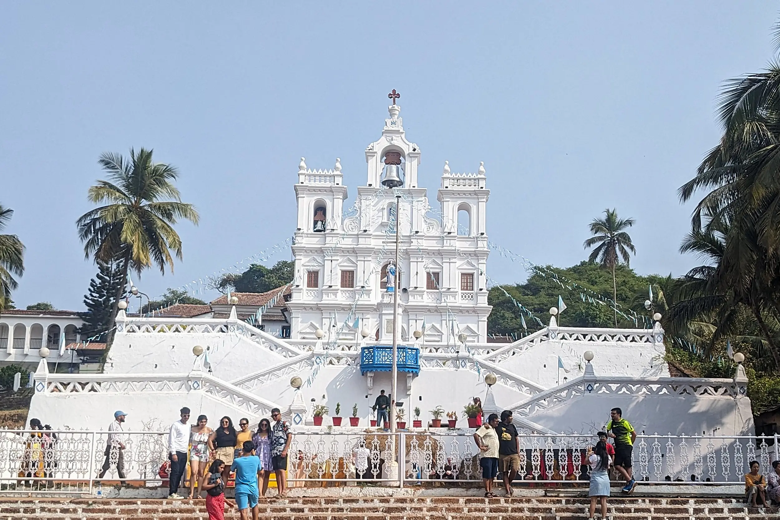 Our Lady of the Immaculate Conception Church a baroque style Portuguese church from the 1600s is painted fully white with crisscross stairs leading up to it. It is surrounded by greenery and palm trees - Our Lady of the Immaculate Conceptions Church, Panaji, Goa, India. things to do in Panaji