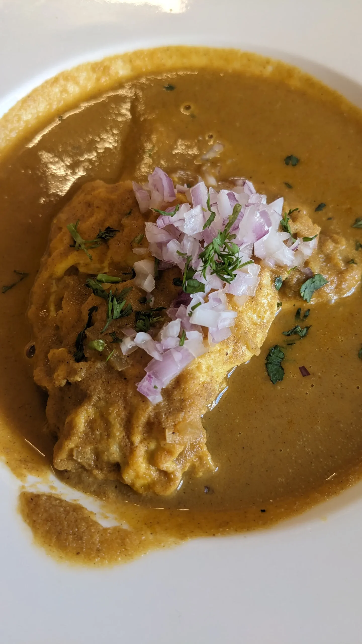 Ros omelette a bowl of Goan classic breakfast - ros omelette. An omelette covered in a curry and topped with fresh red onion and herbs. restaurants in Panaji, Goa, India