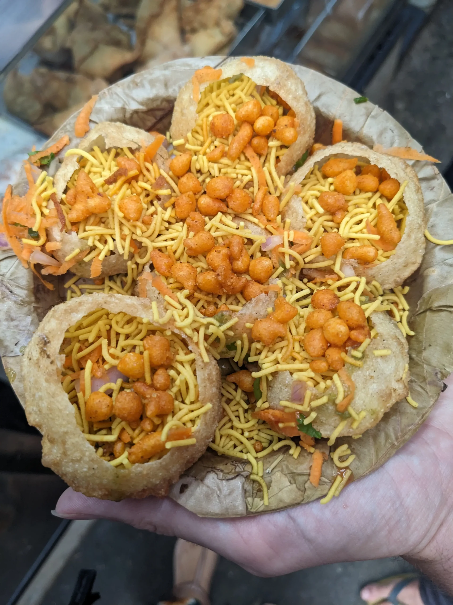 crisp, hollow dough balls filled with crispy sev (fried noodles), fresh onions, served on a dried leaf plate. Sev puri in Mysore, Karnataka, India