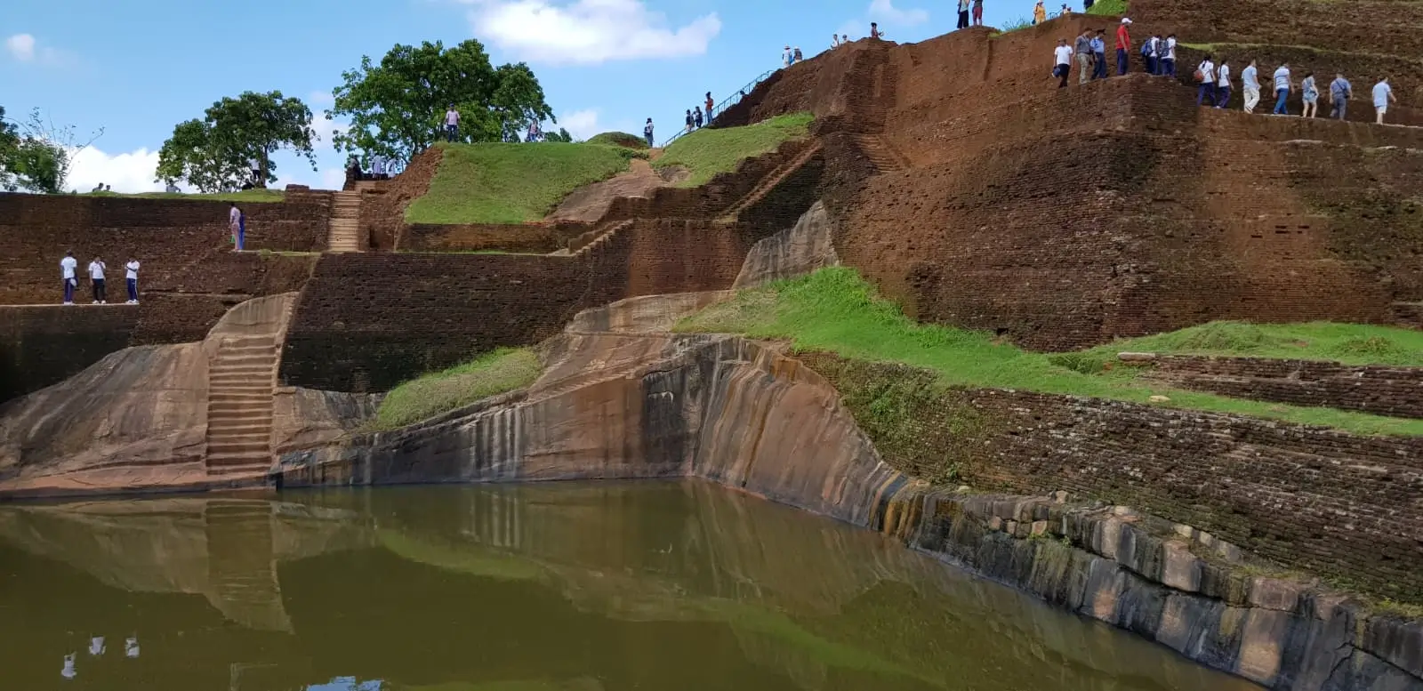 ruins of an ancient citadel shows worn stairs, pools and brick walls on Sigiriya Rock