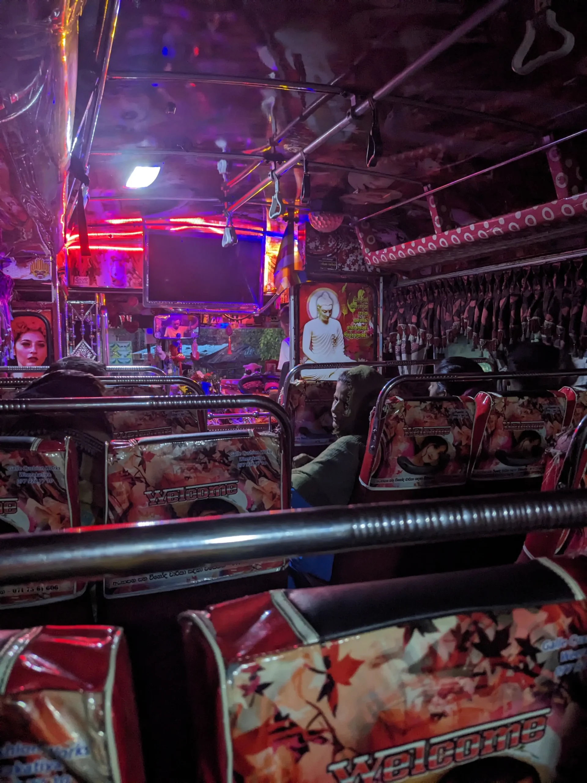 Sri Lankan 6am Party Bus the interior of a local Sri Lankan bus shows pink designs of patterns, people and gods, on the seat covers, head rests, walls and ceiling. There are bright colourful lights and a disco ball.