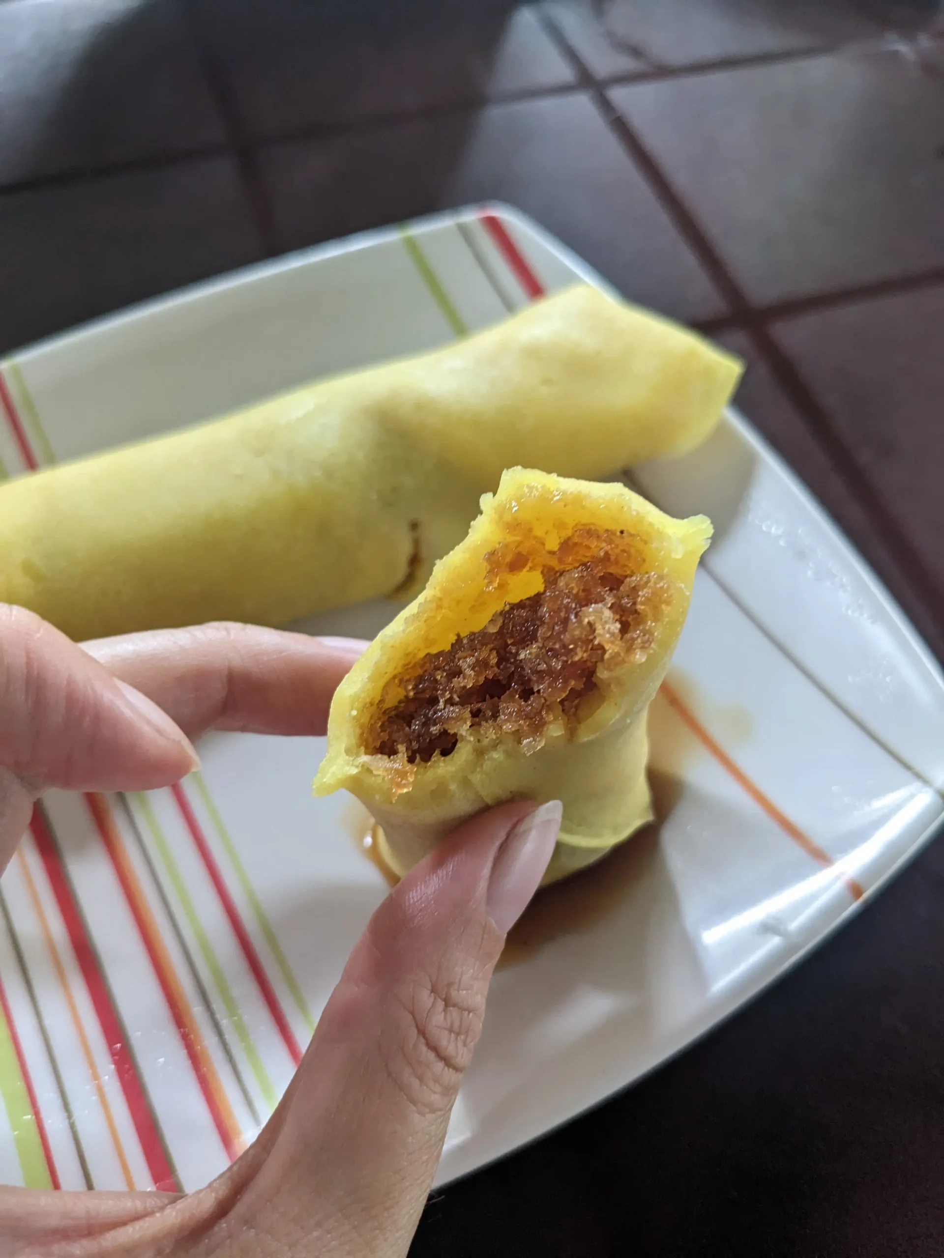 thin yellow pancakes have been rolled up with a brown filling of jaggery and coconut