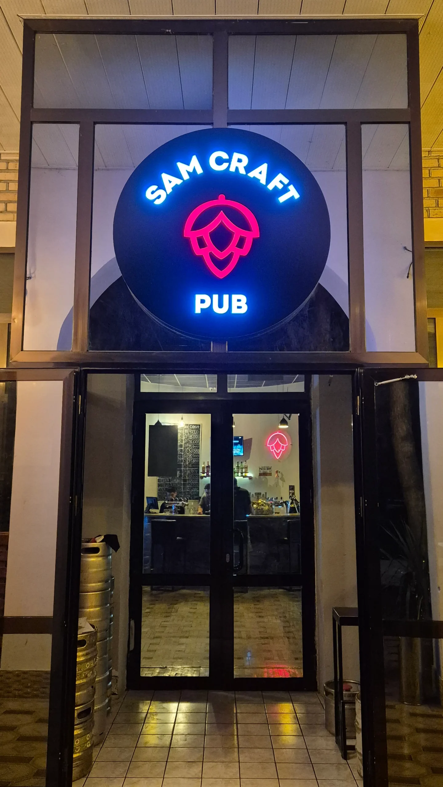 Sam Craft Beer a sign for a pub has the name 'Sam Craft Pub' and a picture of hops at the entrance way in Samarkand