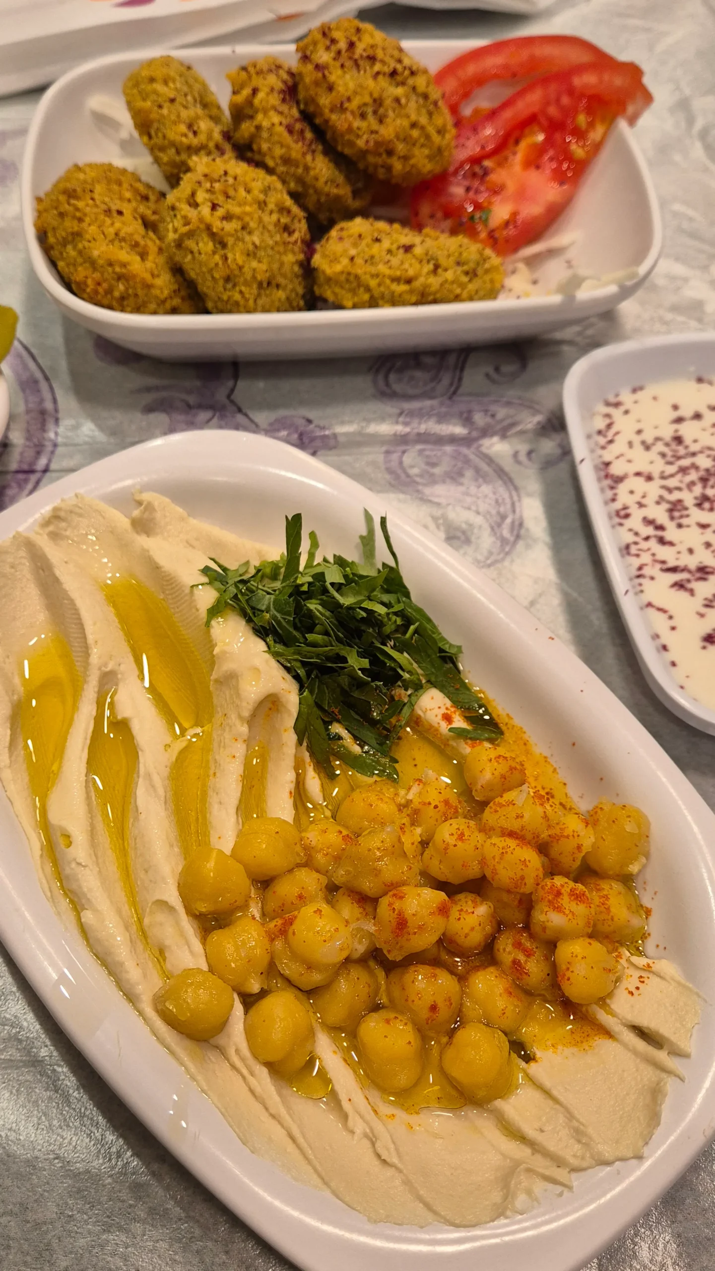 hummus and falafel a plate of creamy hummus topped with olive oil, boiled chickpeas, herbs and a sprinkle of chilli powder