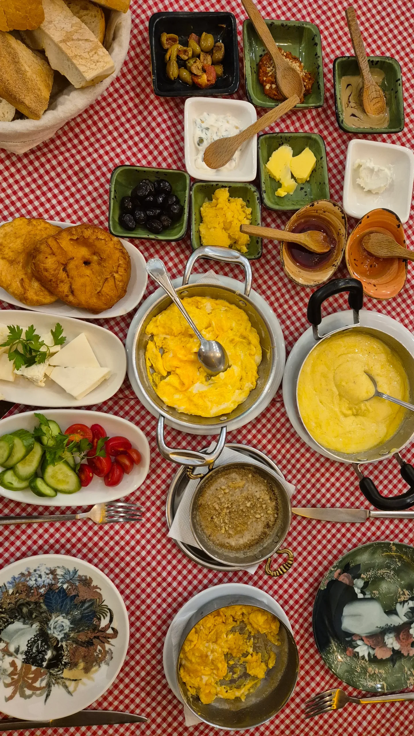 Van Kurdish breakfast Van Turkish breakfast spread on a red and white checked tablecloth. small bowls of jams, honey, cream, olives, butter, muhammara, tahini, muhlama, scrambled eggs, cheese, tomato, cucumber, bread at Limon Kahvalti Evi, Istanbul