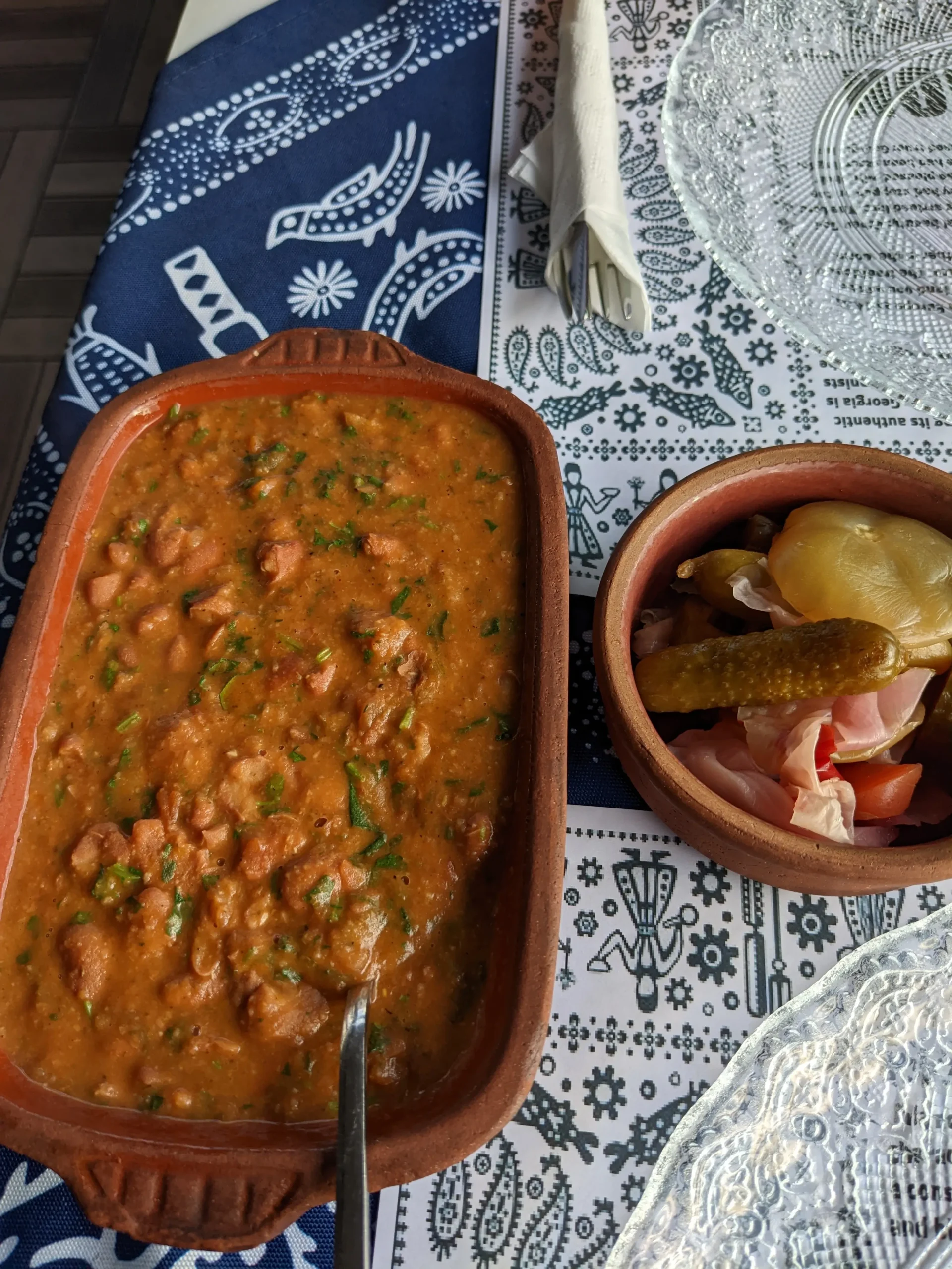 lobio and pickles a traditional Georgian supra (blue and white patterned table cloth) has a clay dish of lobio (herby bean stew) and a pot of pickles at Galaktion, Istanbul