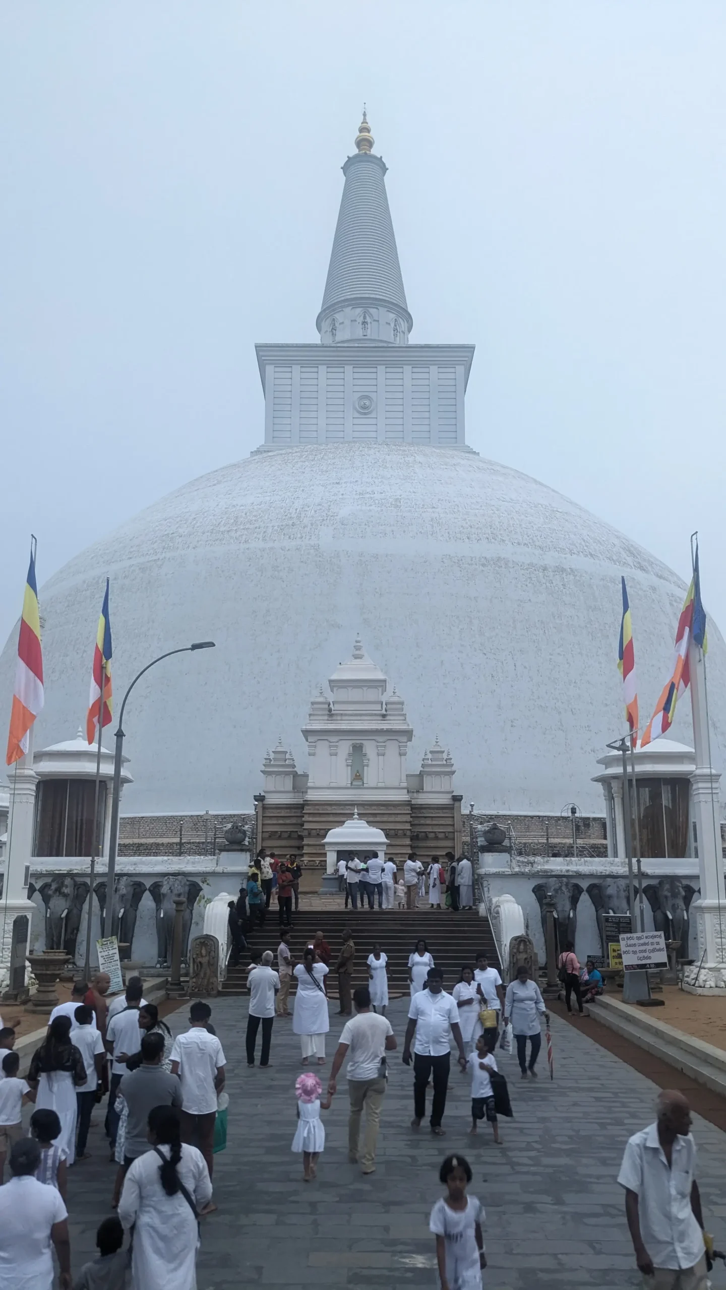 Ruwanwelisaya Stupa, Anuradhapura a huge, white, bell-shaped dagoba has steps leading up to it, crowds of locals, and colourful Buddhist flags - Ruwanwelisaya Stupa, Anuradhapura, Sri Lanka