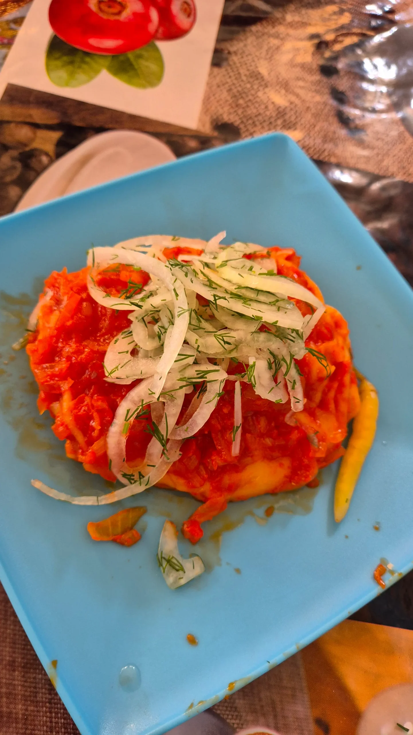 a large Uzbek ravioli (called khanum) is topped with tomato sauce and pickled onions at Chorsu Bazaar, Tashkent