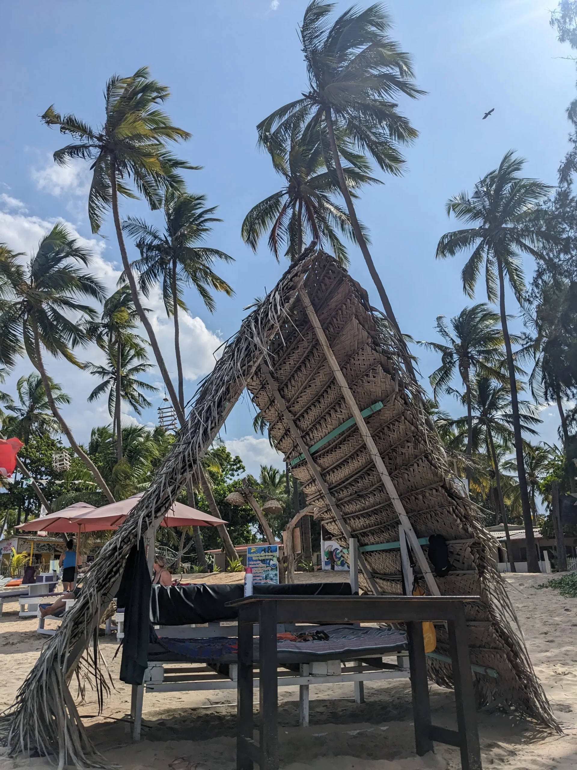 Uppaveli Beach a small wooden shelter from the sun stands over a bench on Uppaveli Beach with palm trees in the background