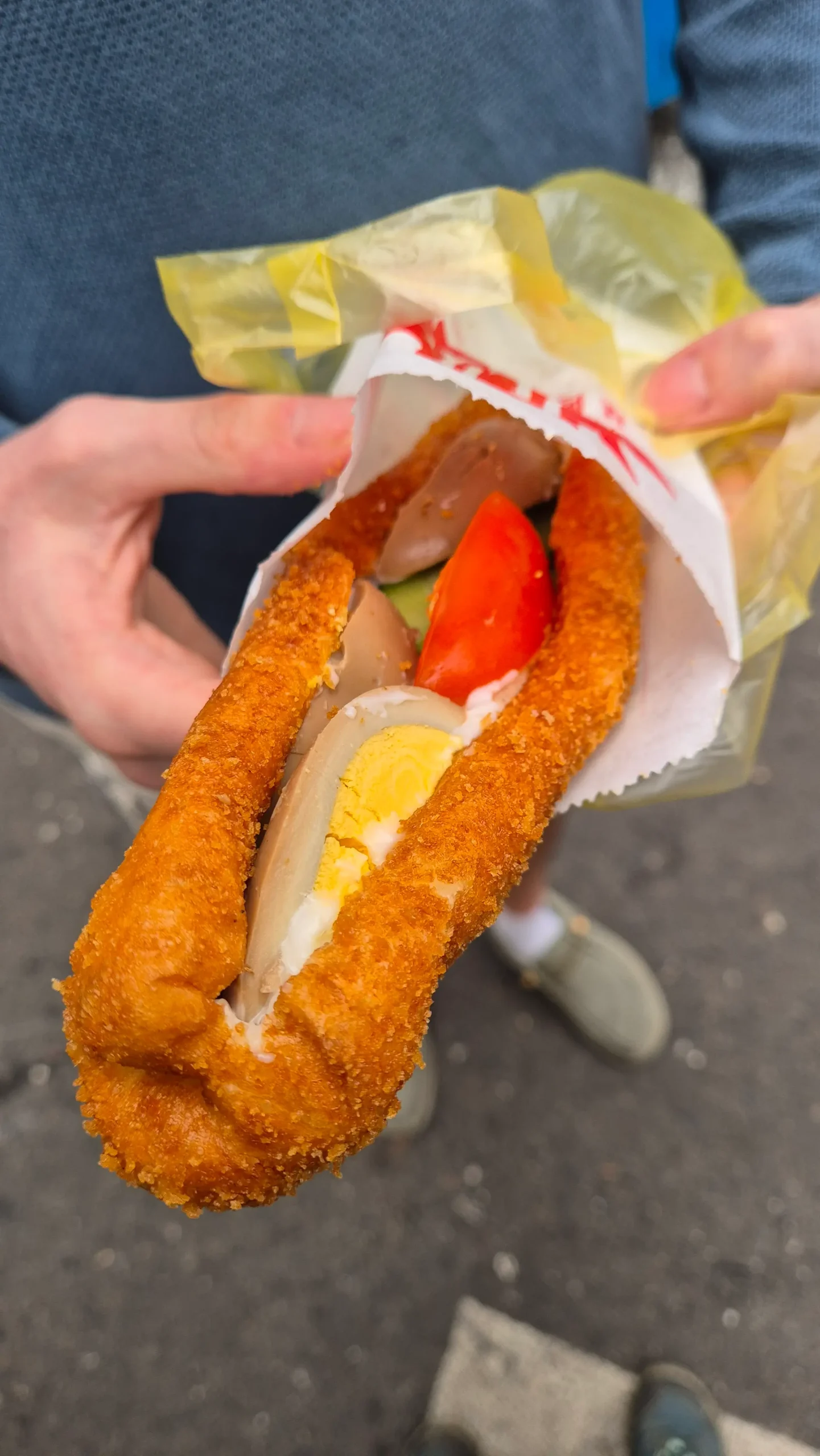a deep-fried dough is split down the middle and filled with mayonnaise, tea egg slices, tomato and cucumber - Taiwanese street food known as a nutritious sandwich