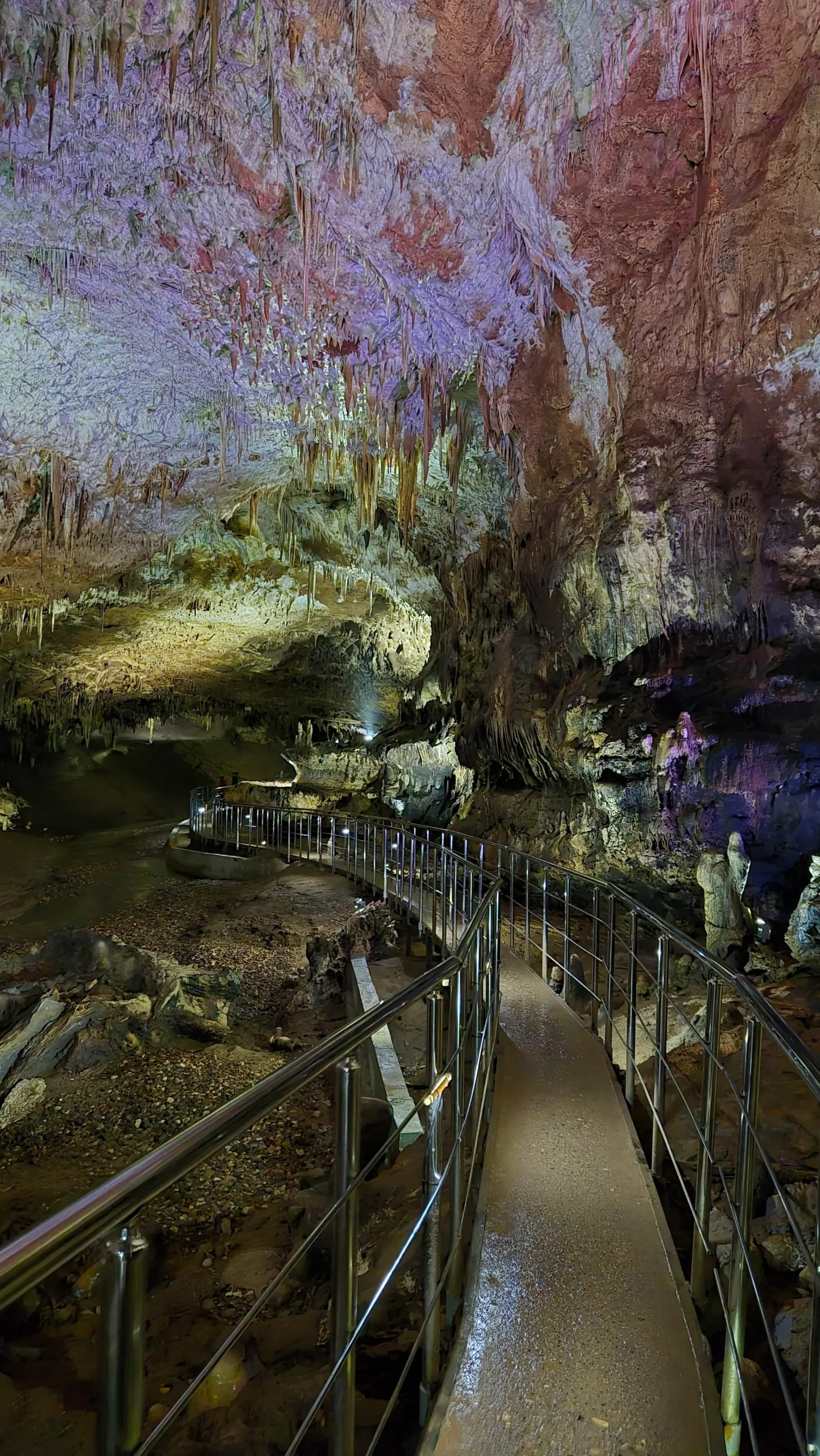 a walkway down the centre of a huge cave with stalactites and stalagmites - Prometheus Cave, Georgia