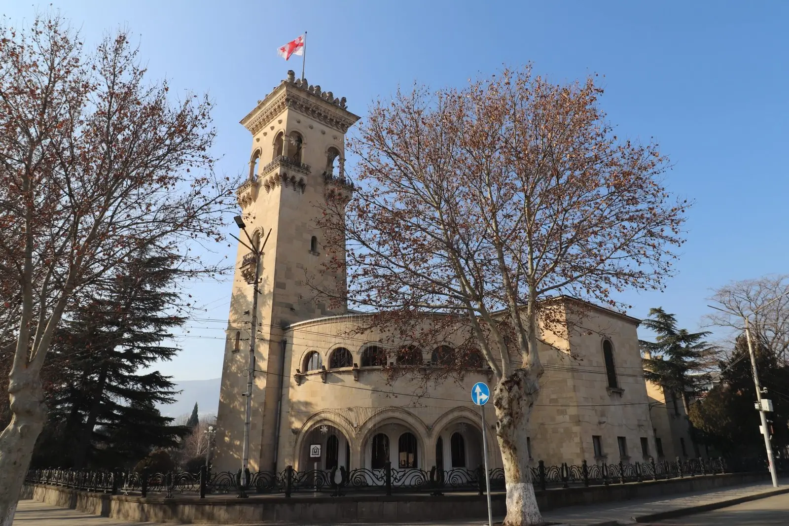 a large brick buildings has a tower and a Georgian flag - Stalin Museum in Gori, Georgia
