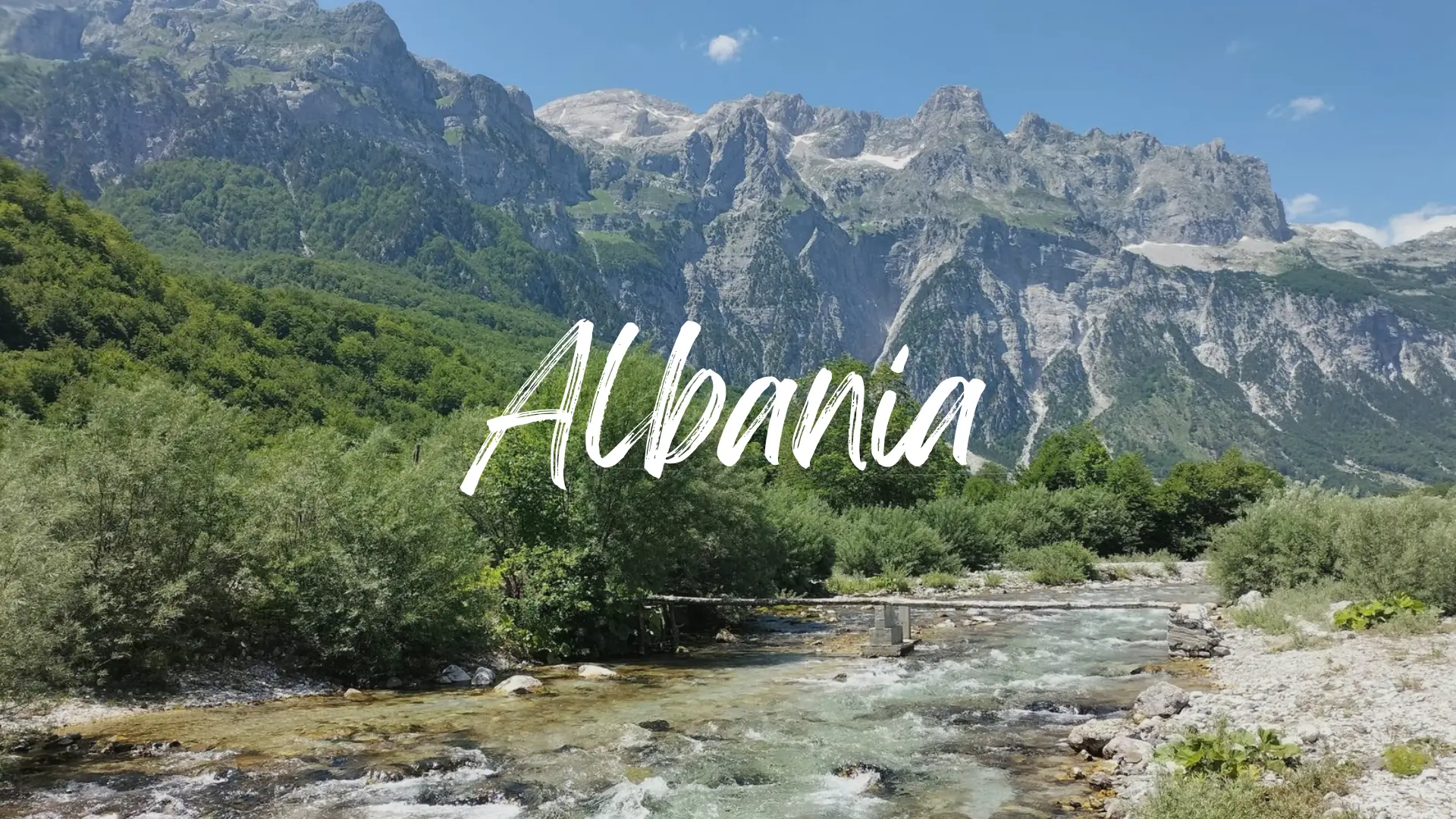 Albania Travel Guide 8 a scenic view of the mountains of the Albanian Alps with a clear mountain river and a makeshift wooden bridge. Albania travel guide