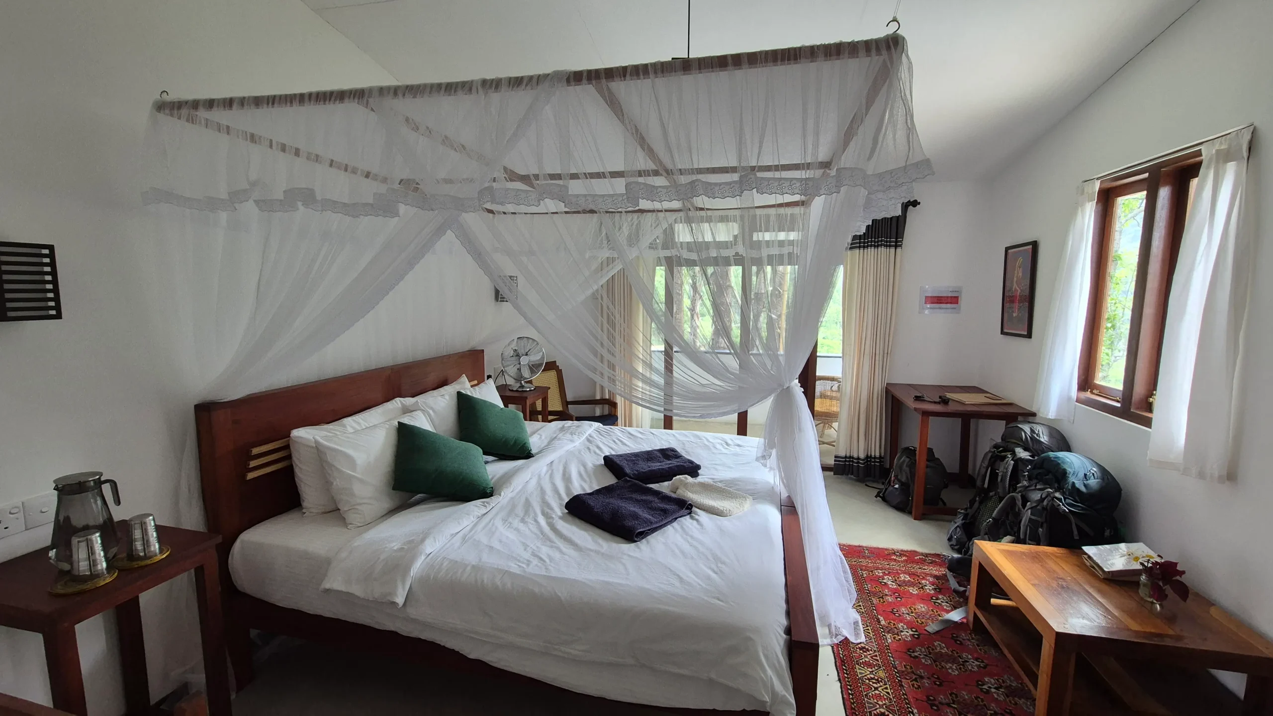 Clove Tree Cottage a wooden bed with white bedding has a suspended mosquito net hanging decoratively from the ceiling