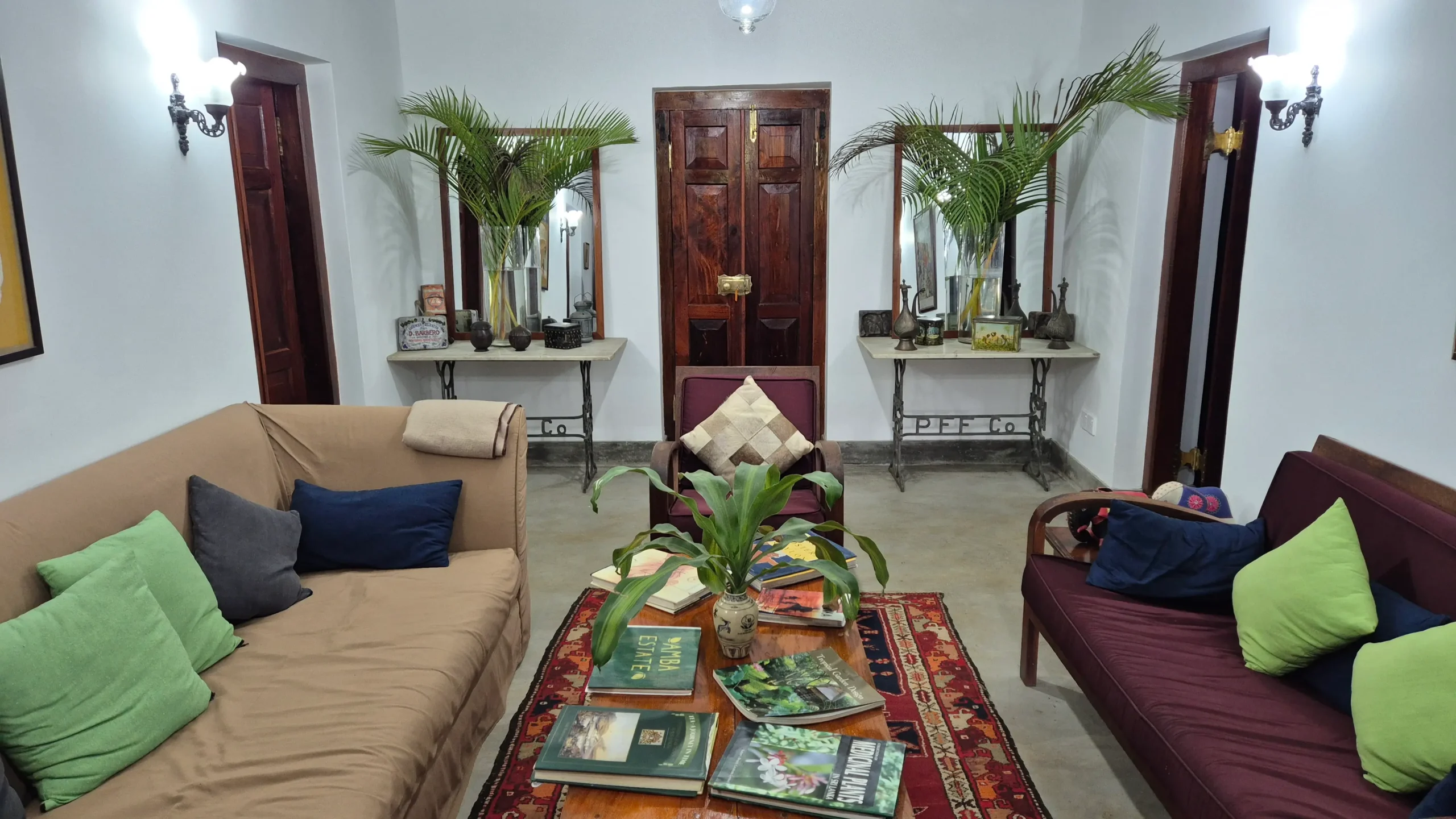 The Farmhouse a lounge area has two sofas and a wooden coffee table. There are books strewn on the table, and plants on vases