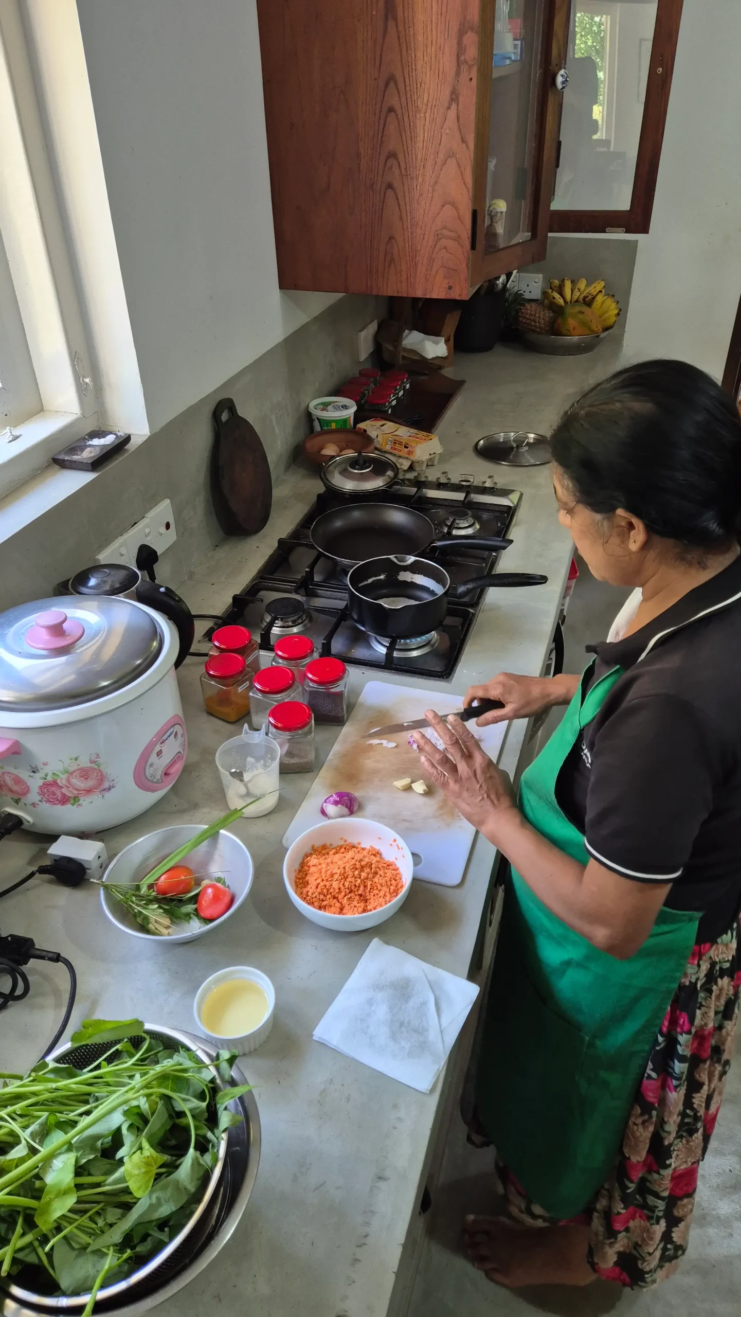 Dal prep a woman is chopping onions in a kitchen with a selection of jarred spices and lentils